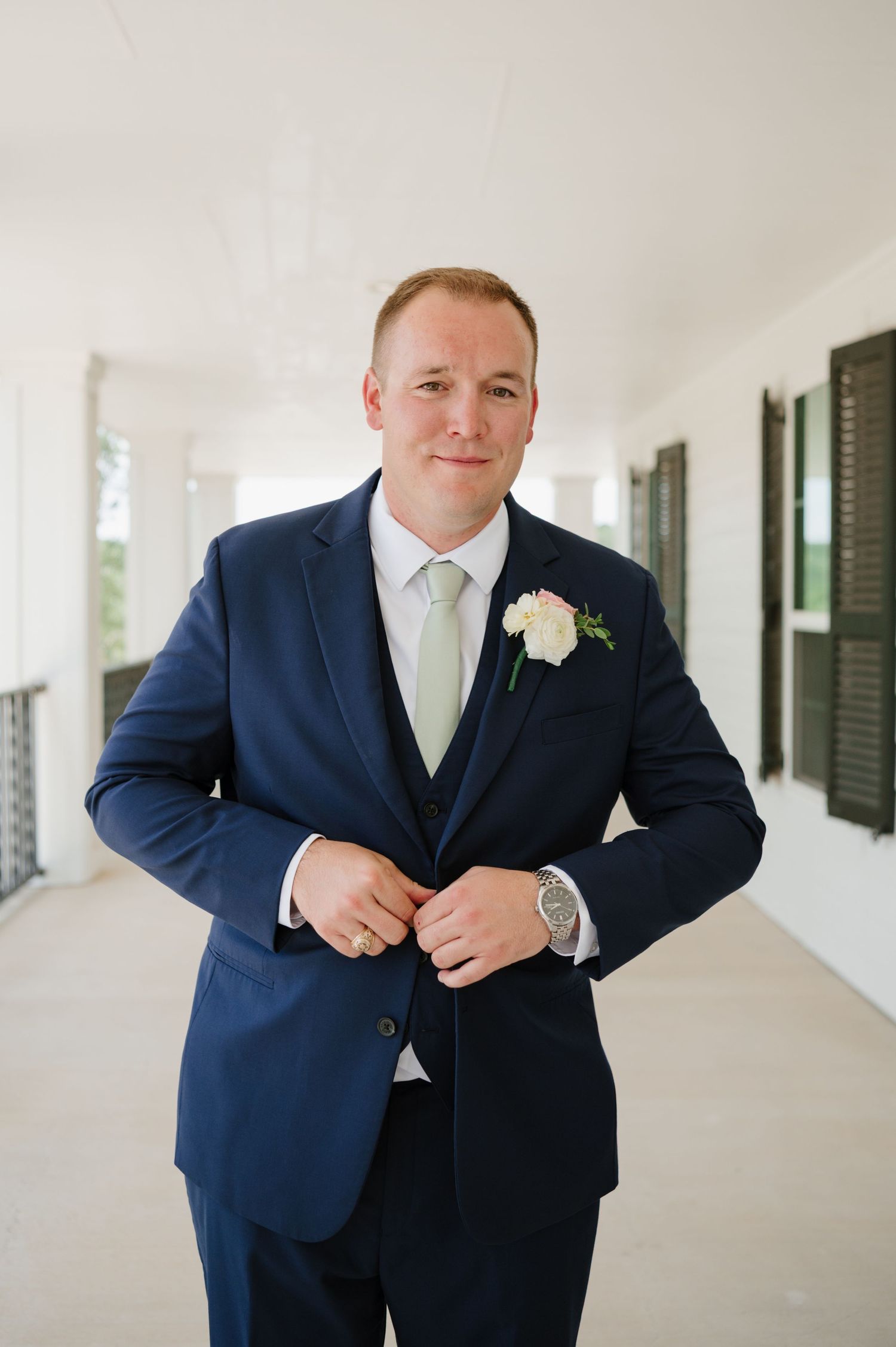 Groom in navy suit adjusting his tie before the ceremony.