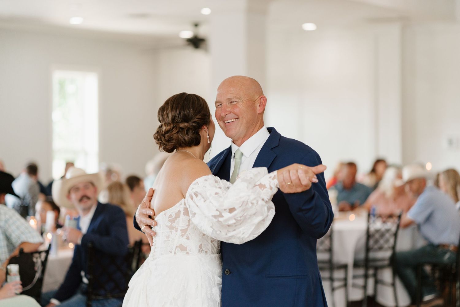 Wedding party celebrates during indoor reception with white decor.