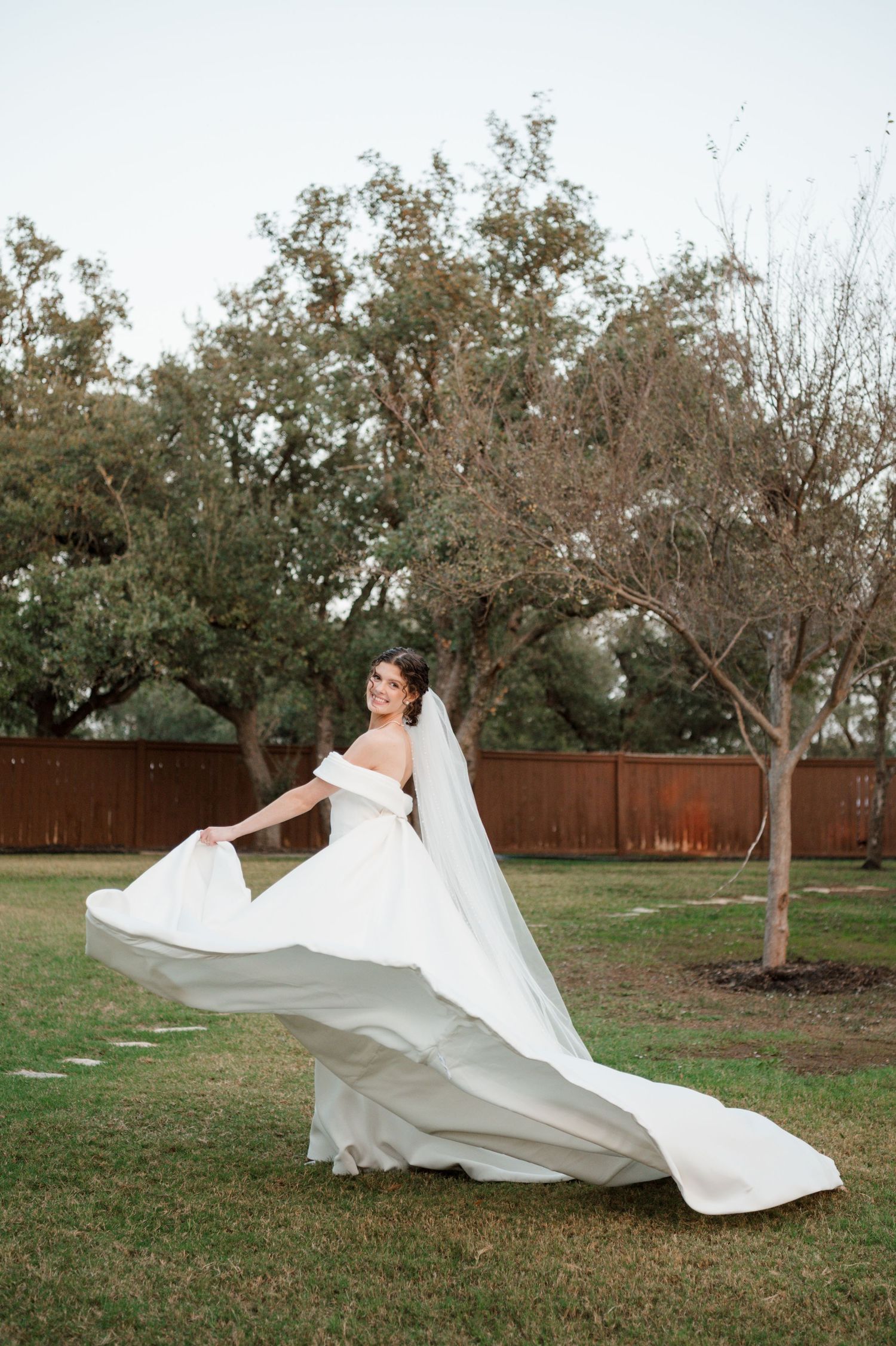 Elegant bridal portraits featuring a flowing white dress veil dramatically captured in motion against a natural backdrop.