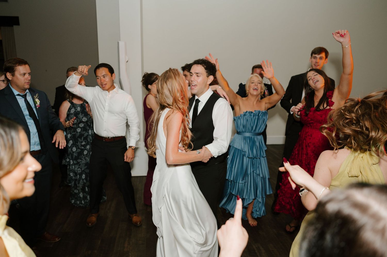 Wedding reception dance floor filled with guests celebrating and dancing together.