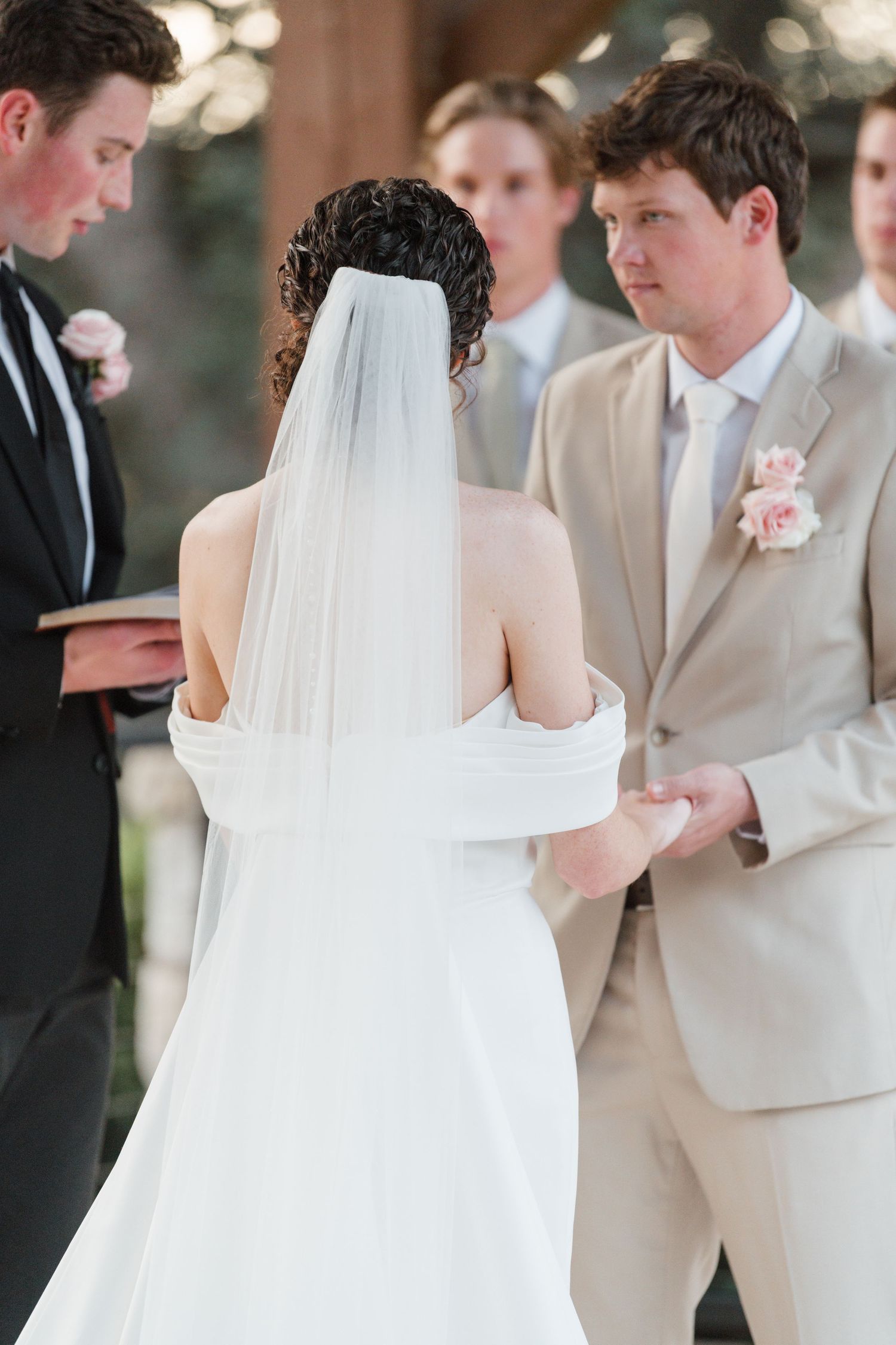 Wedding ceremony sequence showing elegant white bridal gown and tan suits during the vow exchange.