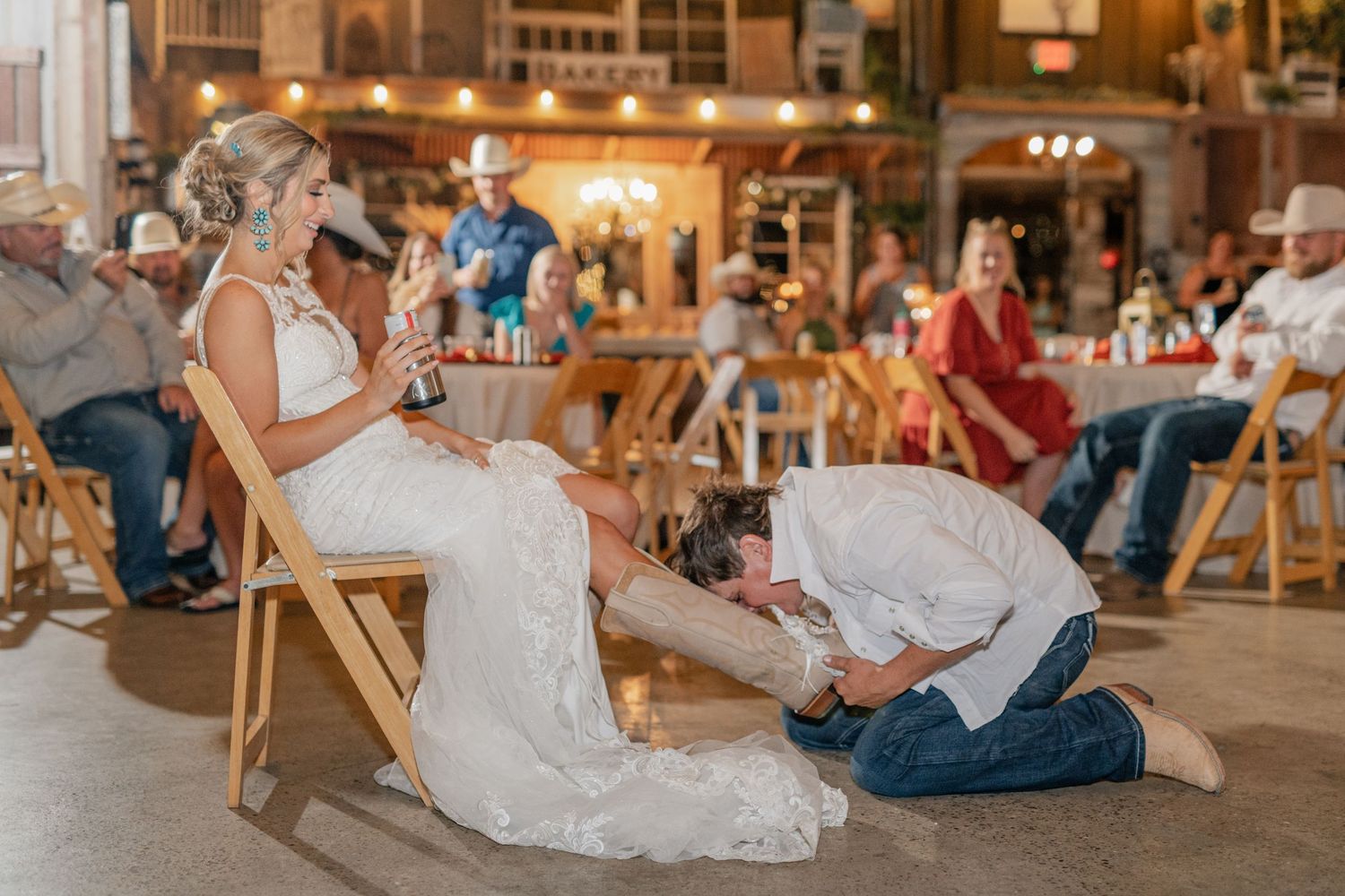 A wedding reception tradition taking place in a rustic barn venue with wooden folding chairs.