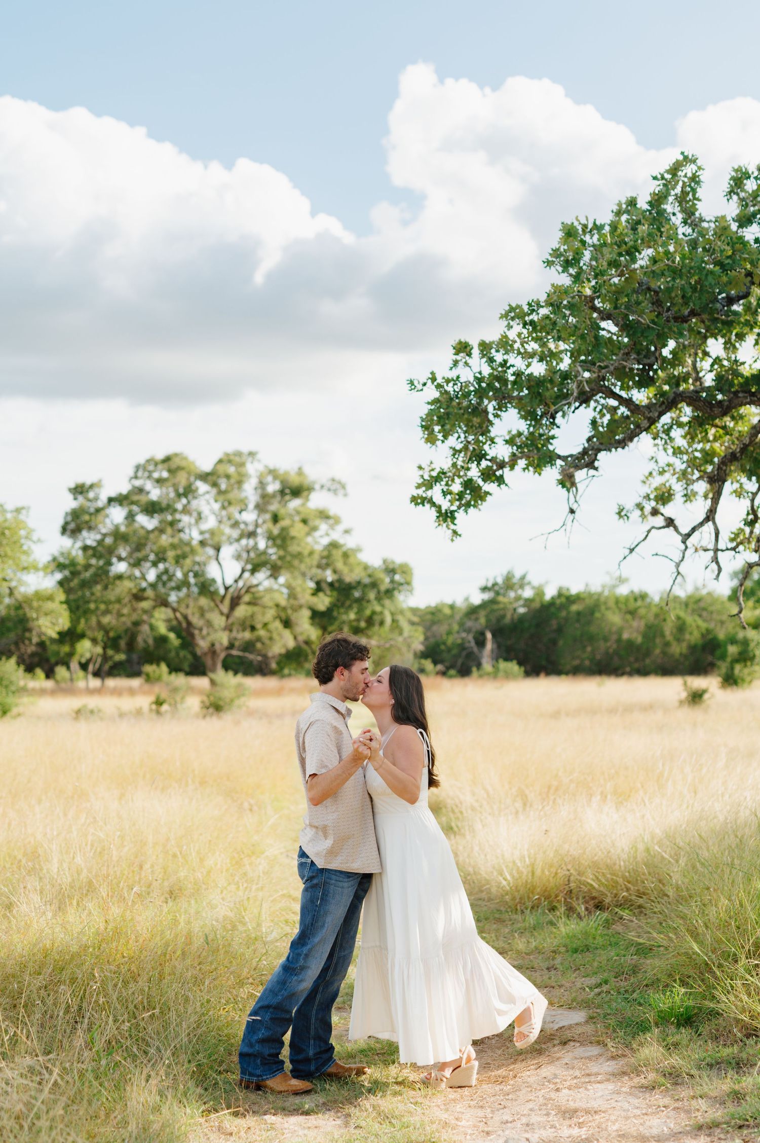 A couple sharing romantic moments while walking through a golden field on a sunny afternoon.
