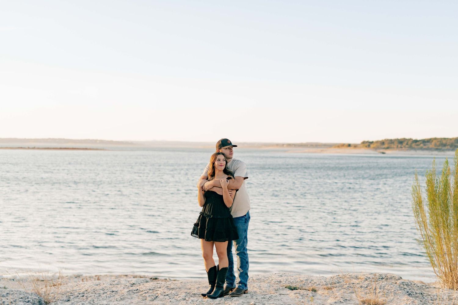 Happy couple sharing an affectionate moment by the water's edge with scenic views.