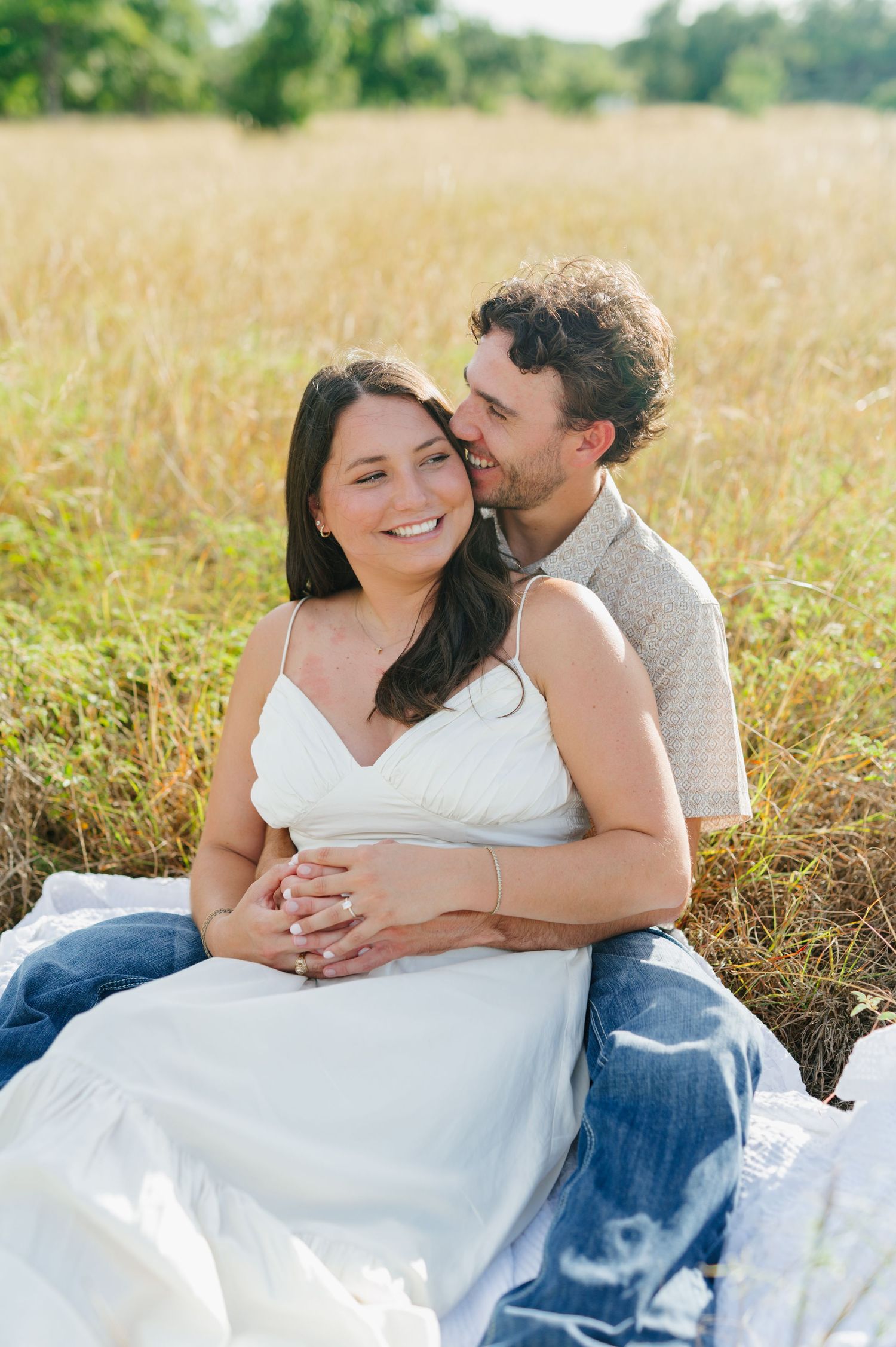 Intimate couple's portrait session in a sunlit meadow with tall grass.