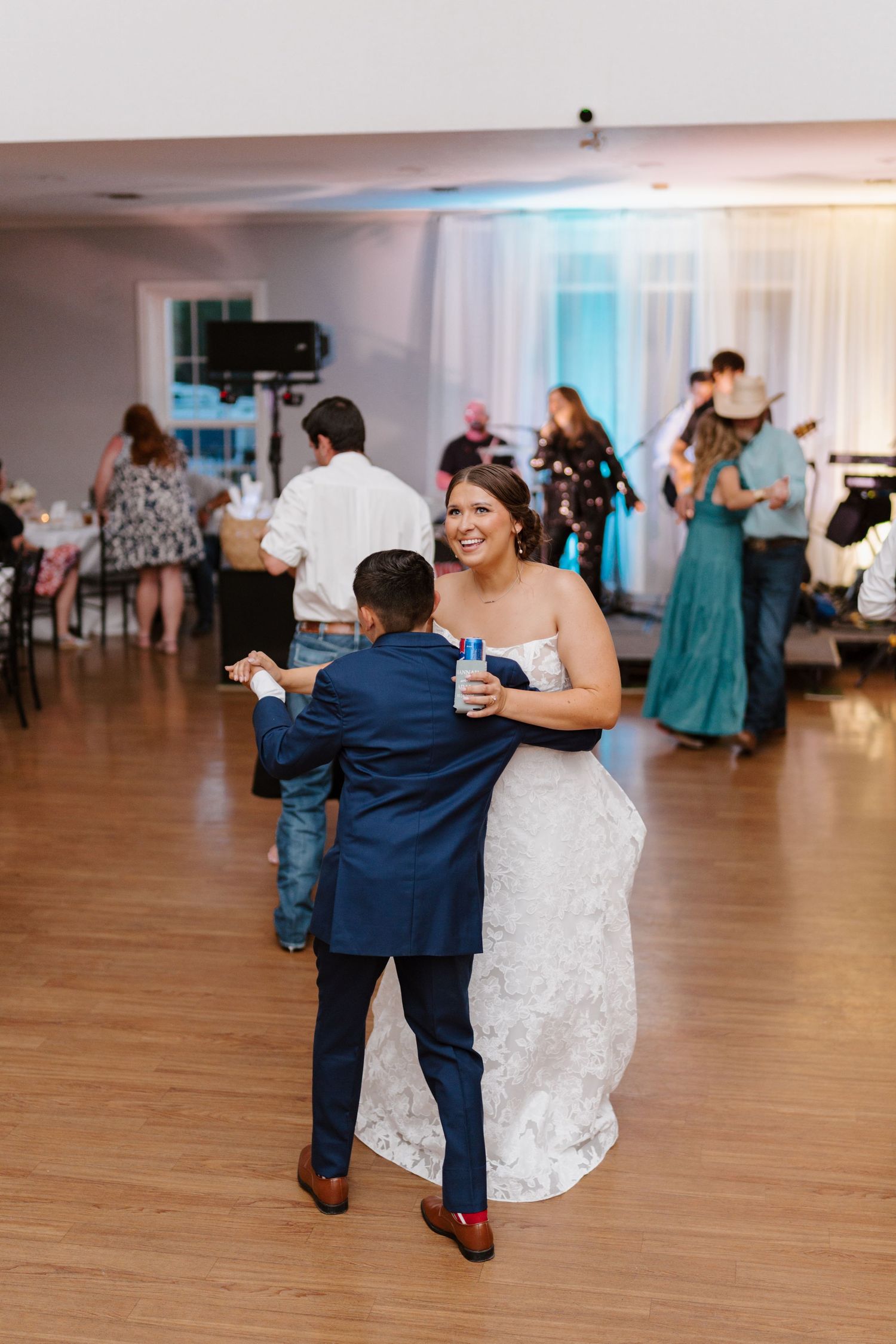 Wedding reception dance floor scene with guests celebrating in an elegant white ballroom.