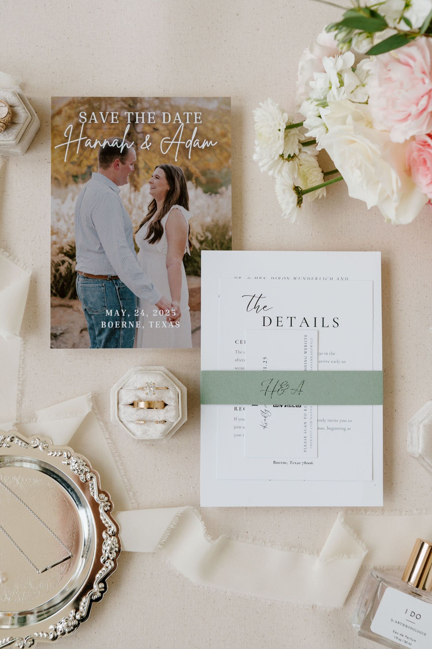 Elegant wedding invitation suite with floral details and save-the-date cards laid out on light fabric.