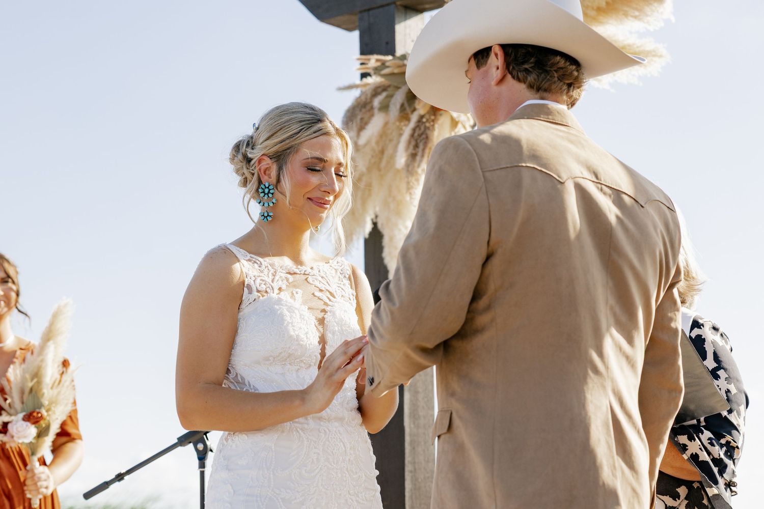 Outdoor wedding ceremony showing exchange of vows under bright blue sky.