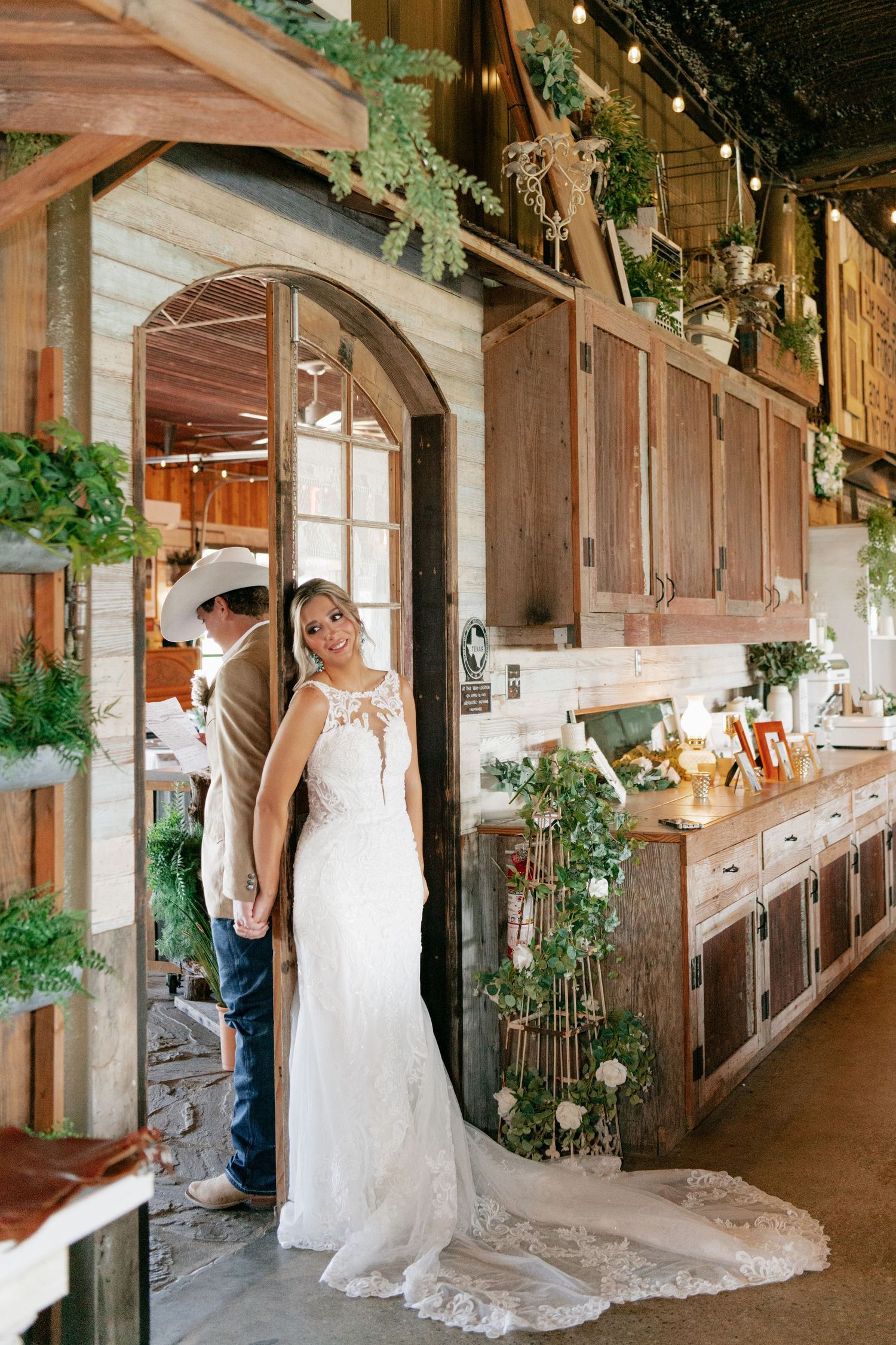 Rustic barn wedding venue with wooden arch doorway decorated with greenery and string lights.