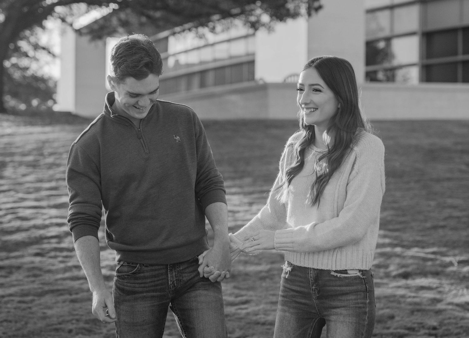 Black and white photo of a couple sharing a joyful moment together outdoors.