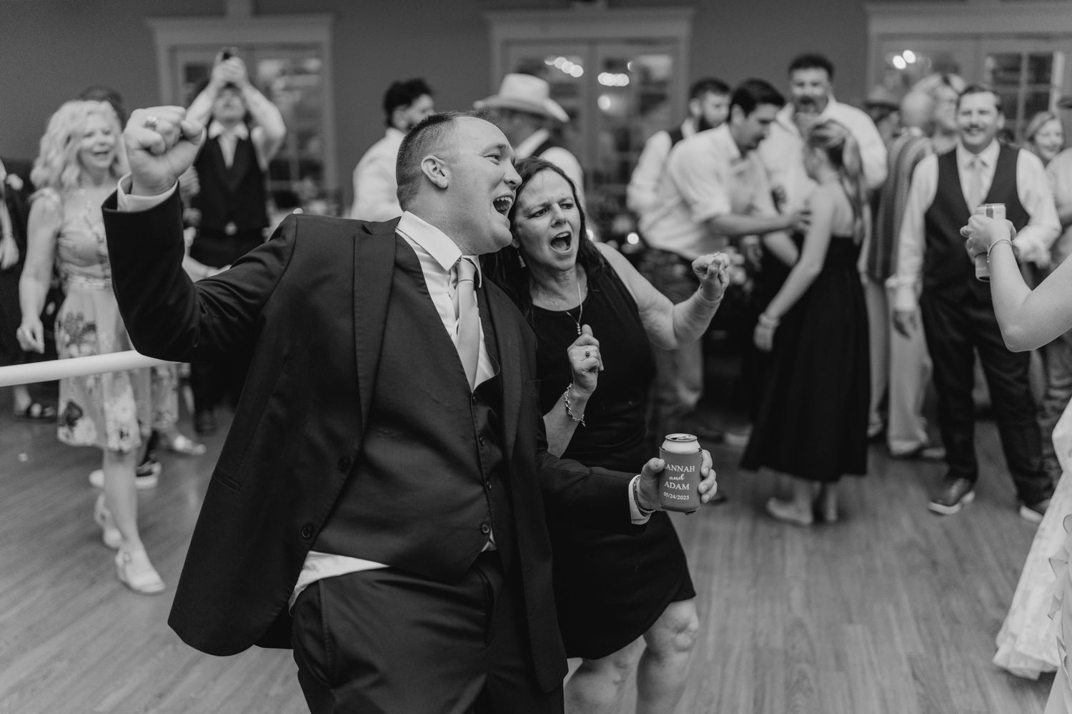 Wedding reception guests dancing and celebrating on a darkened dance floor.