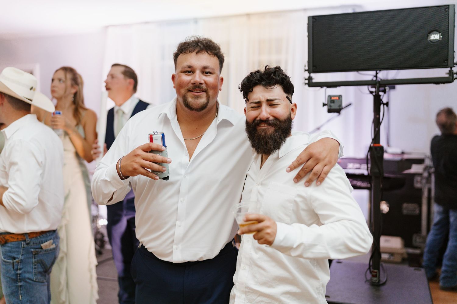 Two guests in white shirts sharing drinks and smiles at the reception.