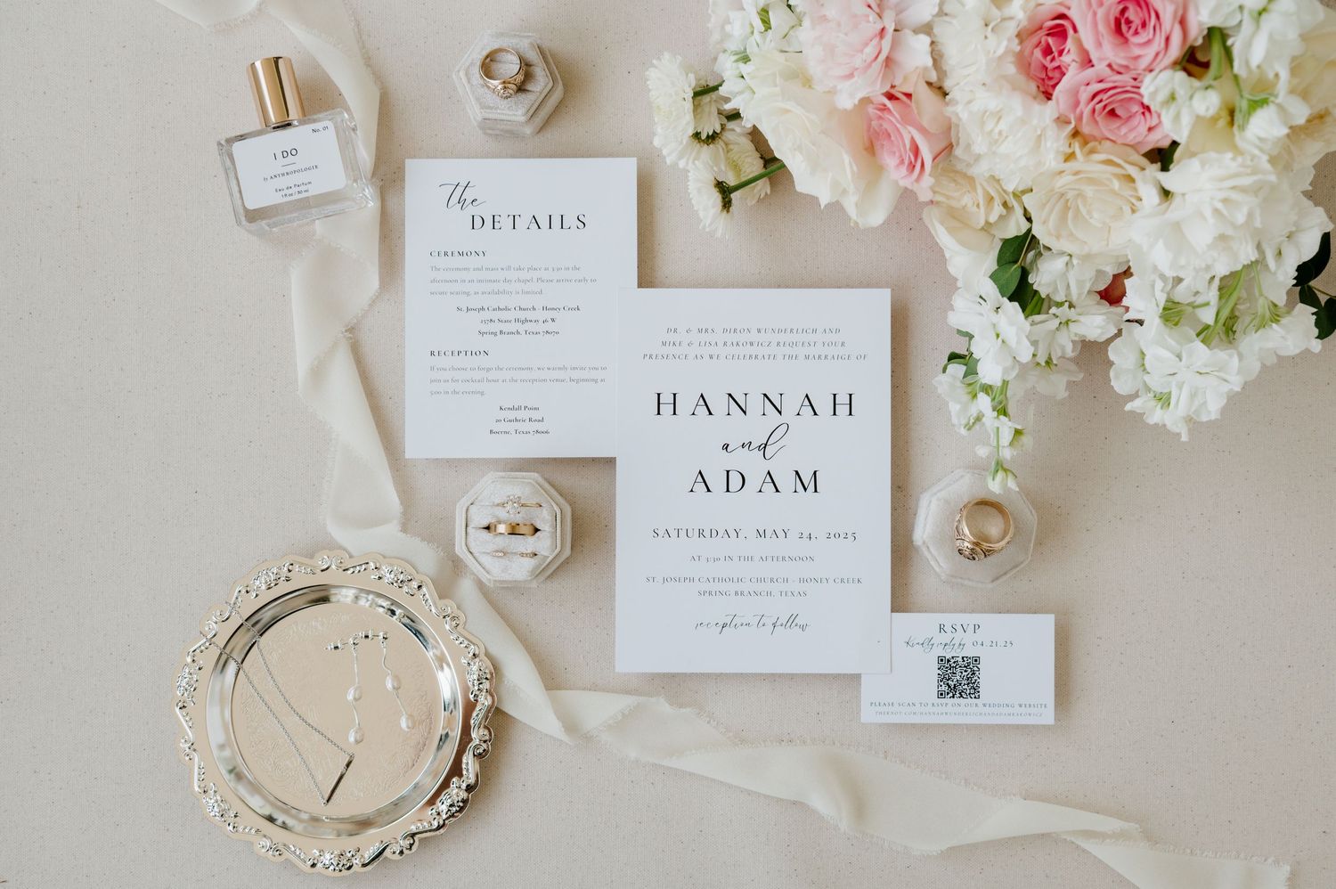 Elegant wedding invitation suite with white stationery, blush floral arrangement and delicate ribbon on neutral background.