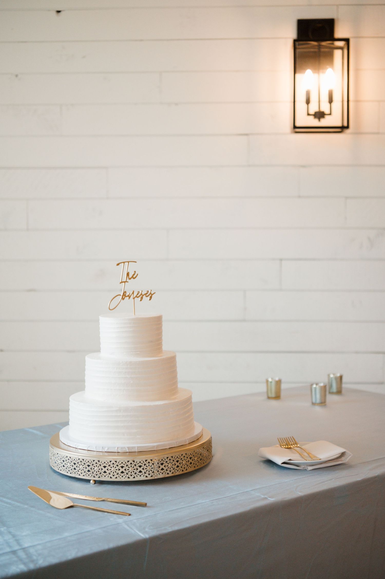 A white wedding cake with floral decorations on a table with other wedding details.