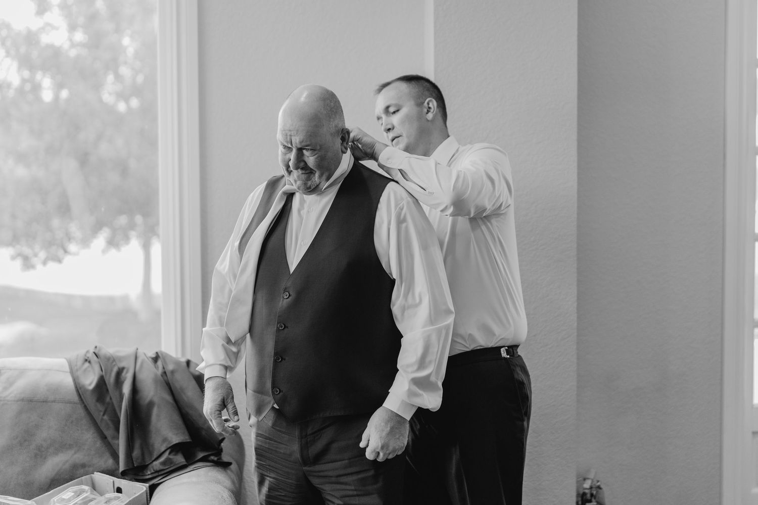 Men in formal attire adjusting suits and ties in preparation for wedding.