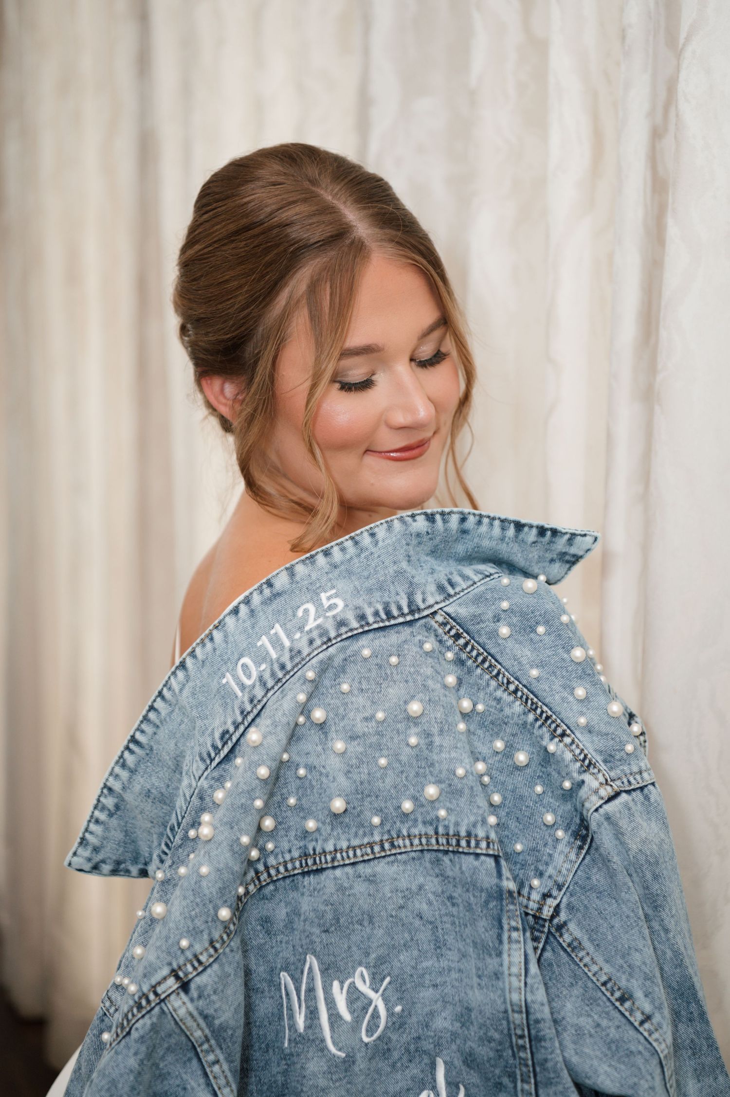 A denim jacket adorned with pearl embellishments and custom 'Mrs' lettering on the back.