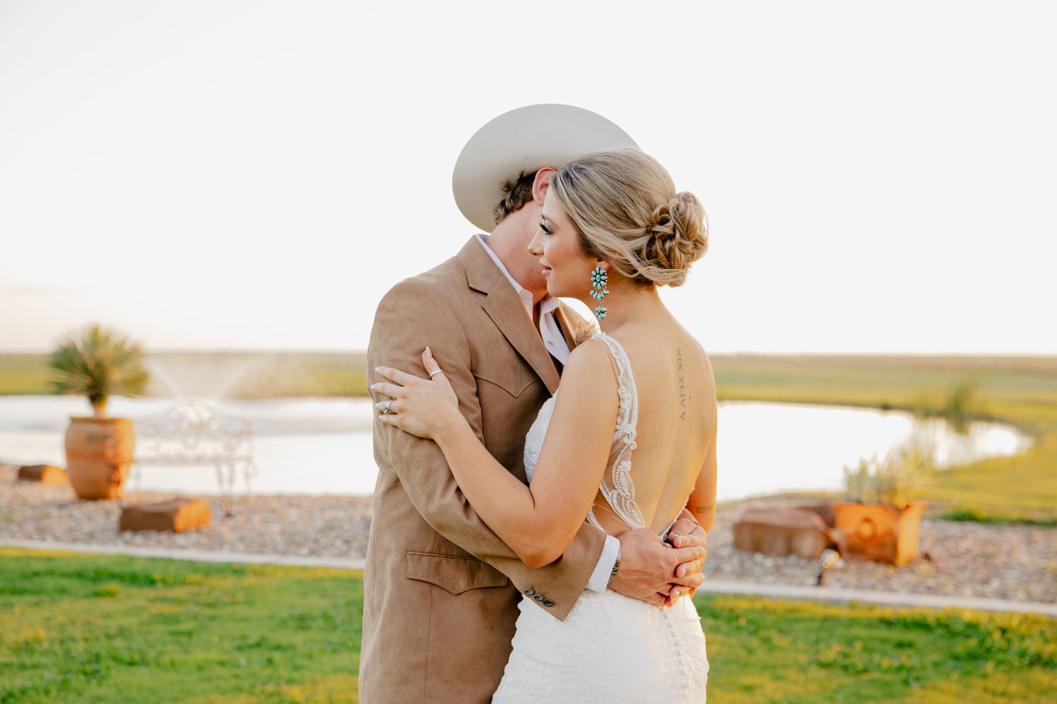 A couple shares an intimate embrace during their rustic outdoor wedding.