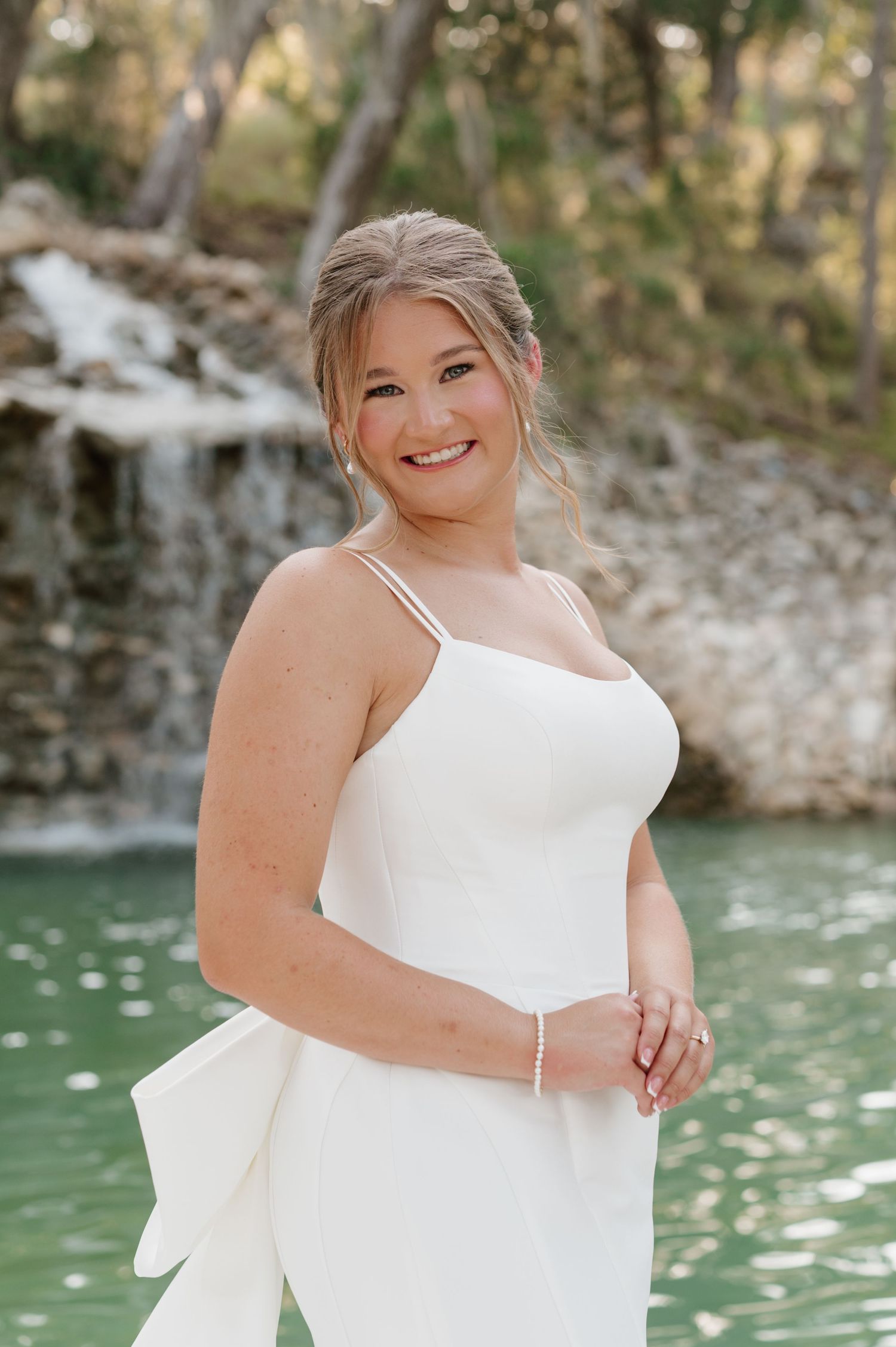 Bridal portraits captured against a scenic waterfall backdrop with turquoise water.