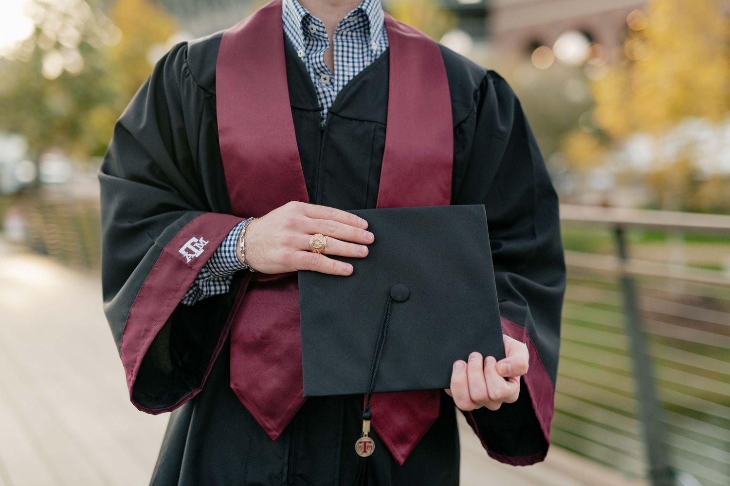 Graduate in maroon stole holds diploma and class ring.