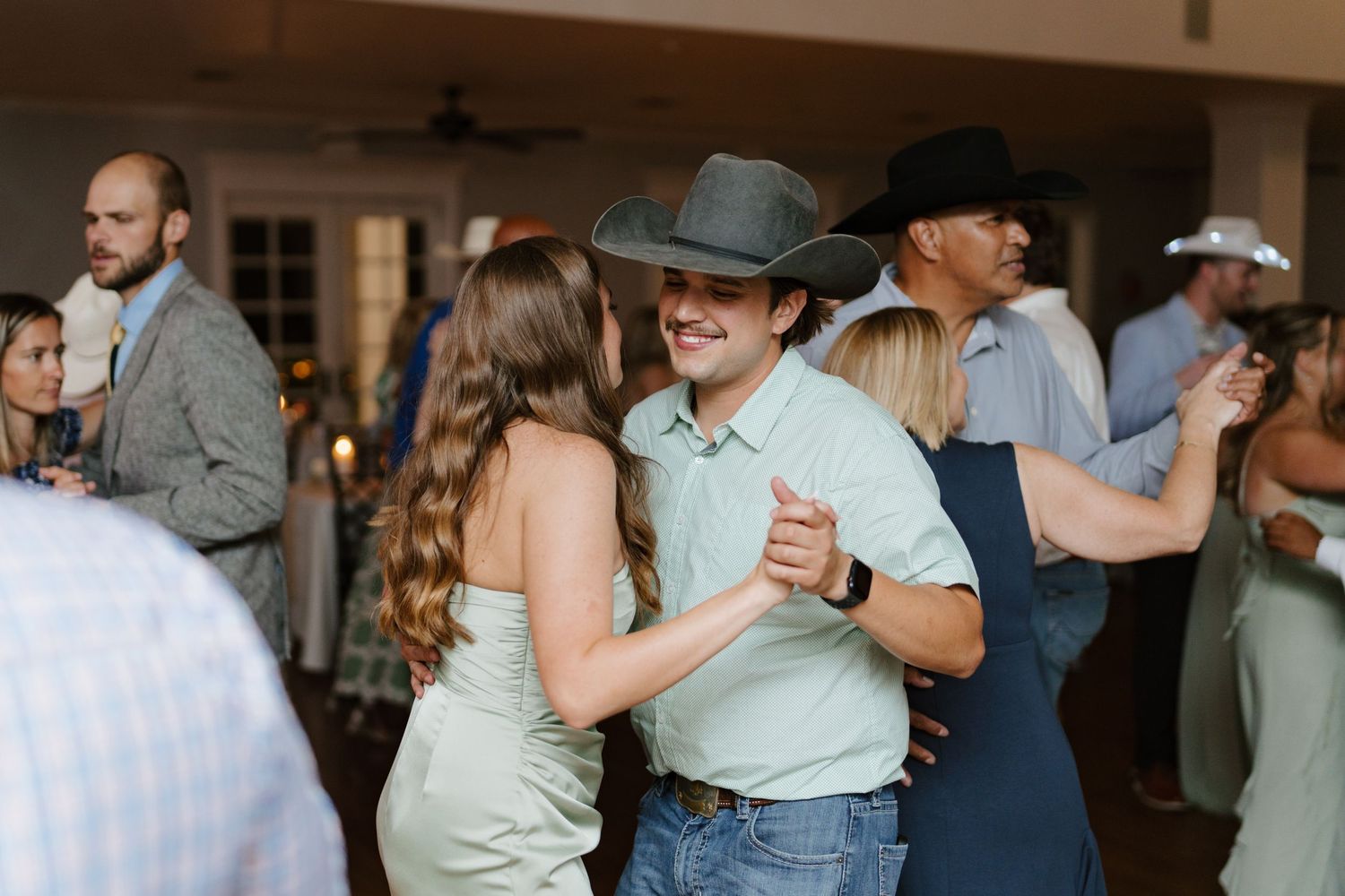 Wedding guests dancing together in casual attire on a warm summer evening at an outdoor reception.