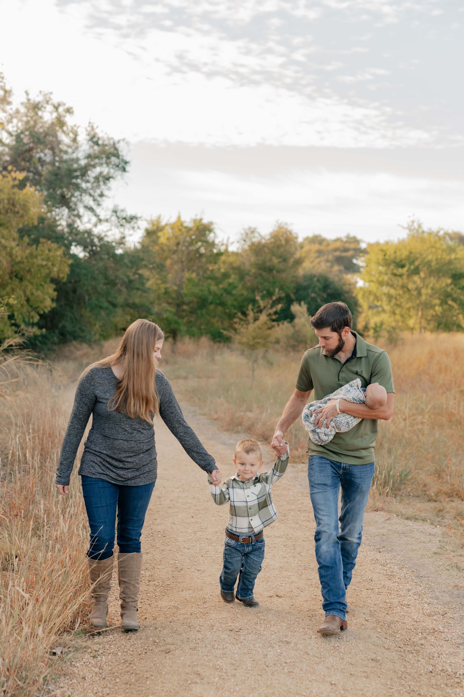 Family strolling down a countryside path while holding hands on an autumn day.
