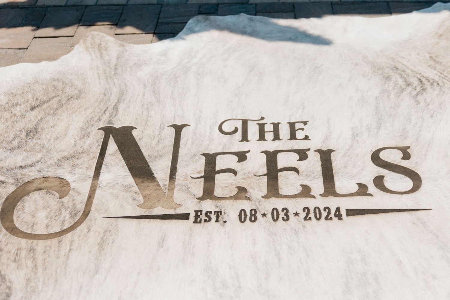 Custom wedding sign showcasing 'The Neels' text with establishment date engraved on white textured background.