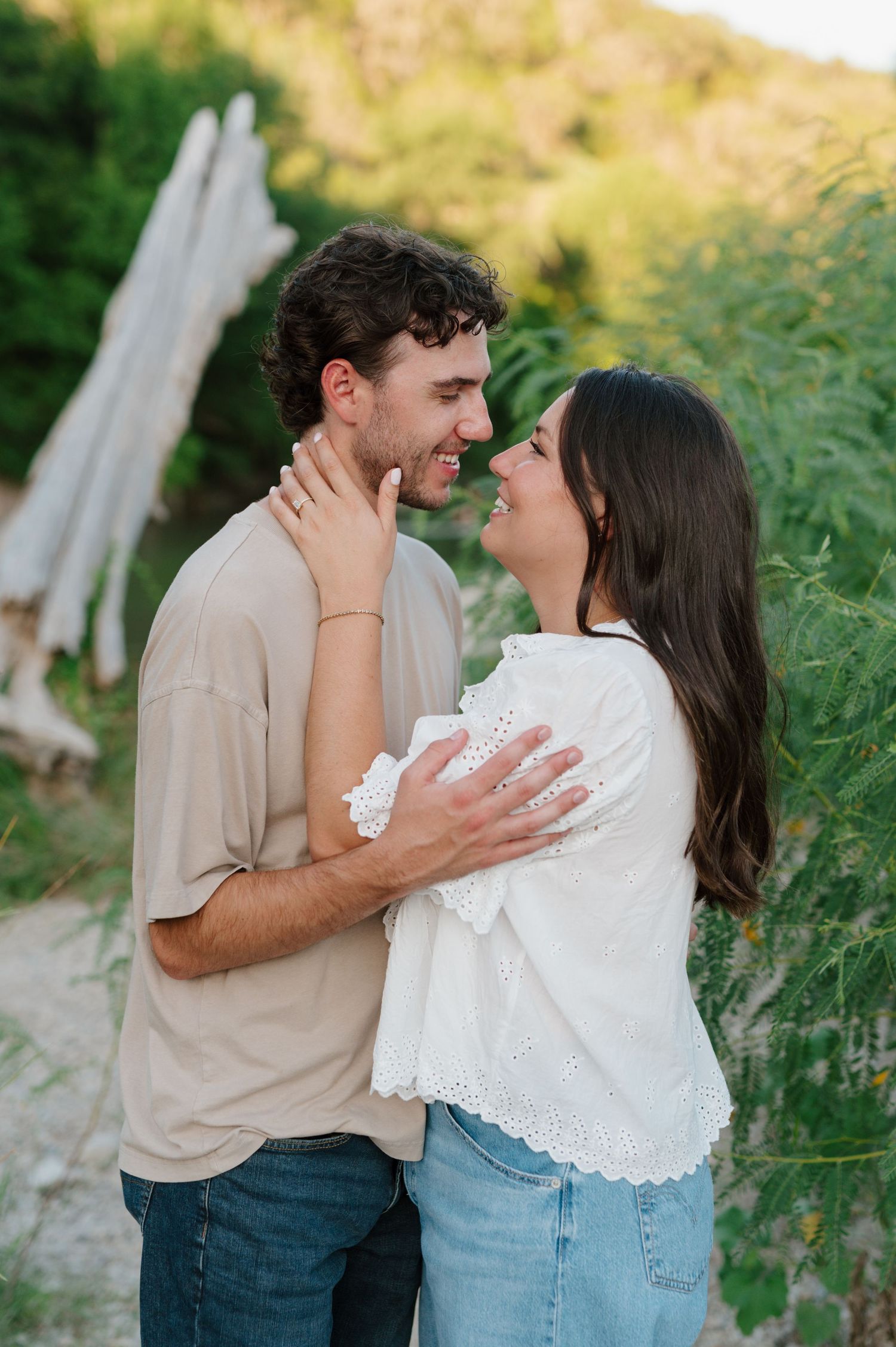 Couple sharing joyful laughs and embraces in a green summer field.