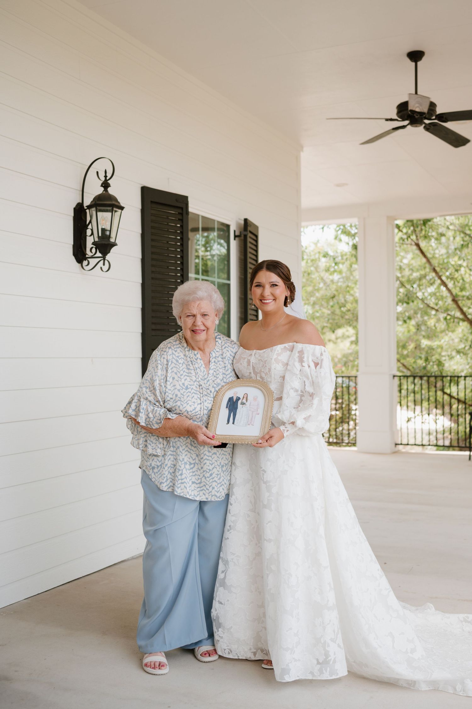 Beautiful white wedding dress displayed on a covered porch with white columns.