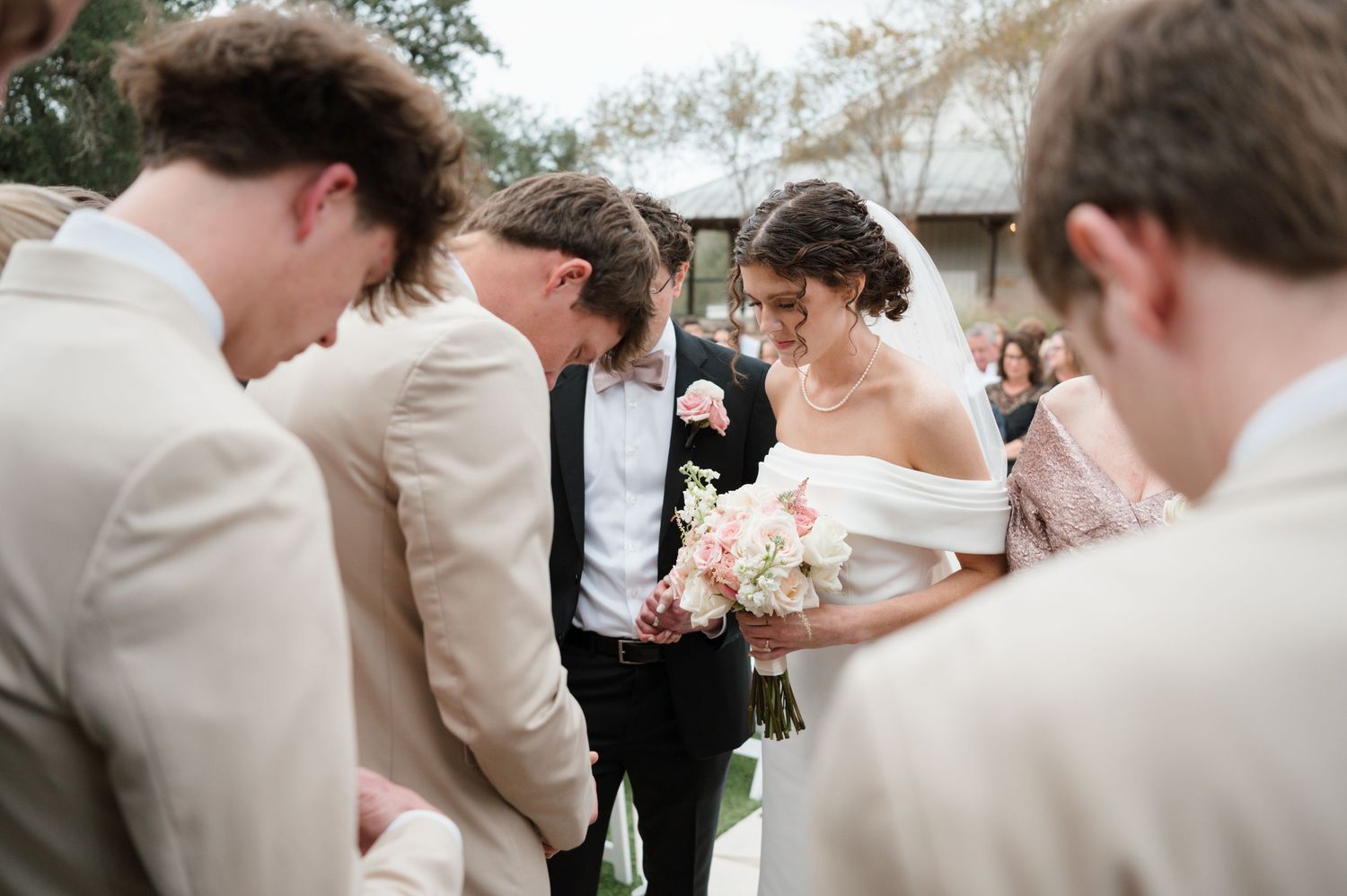 A group gathers for a joyful celebration at an outdoor wedding ceremony with natural greenery in the background.