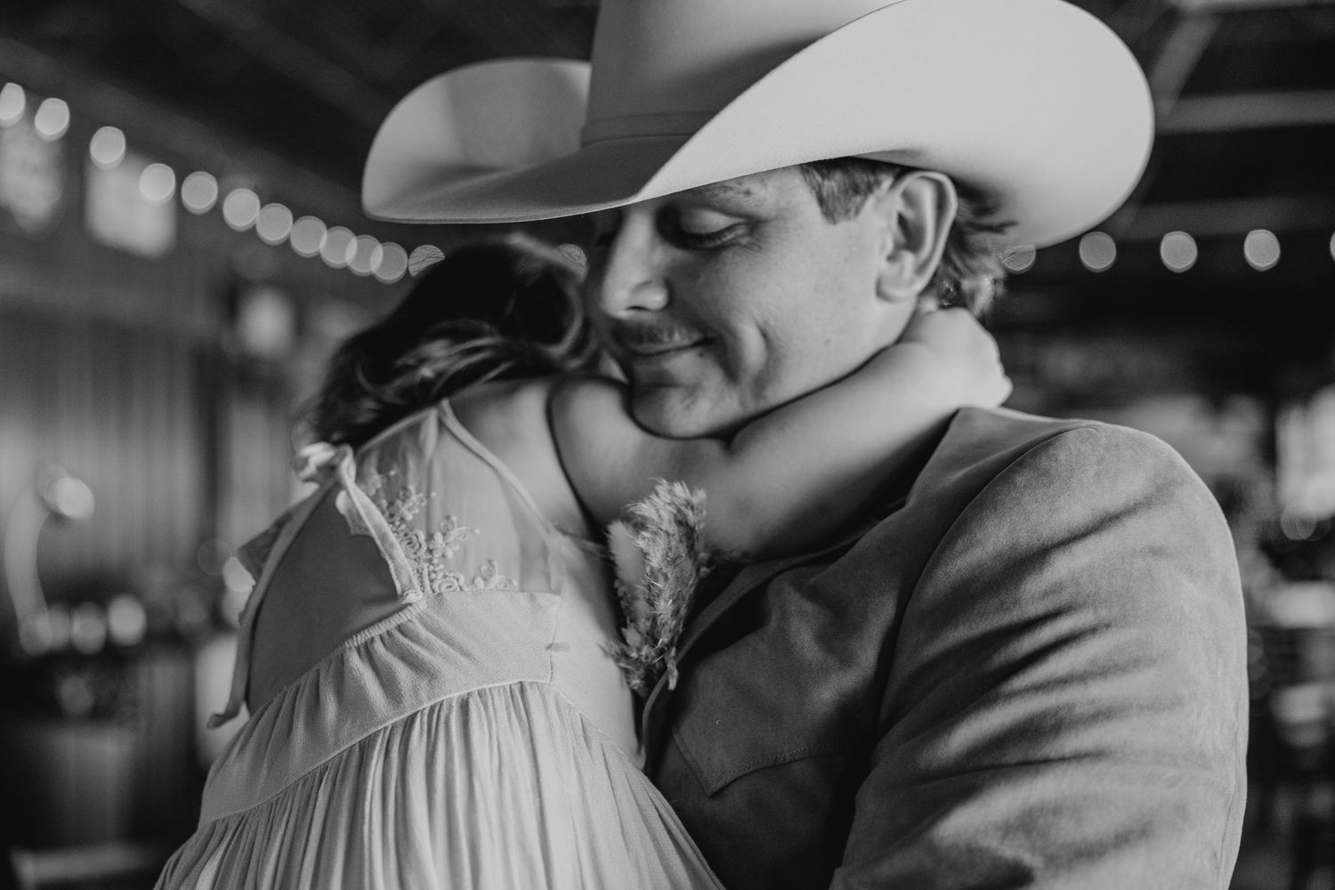 Black and white romantic moment captured in rustic venue with western style attire.