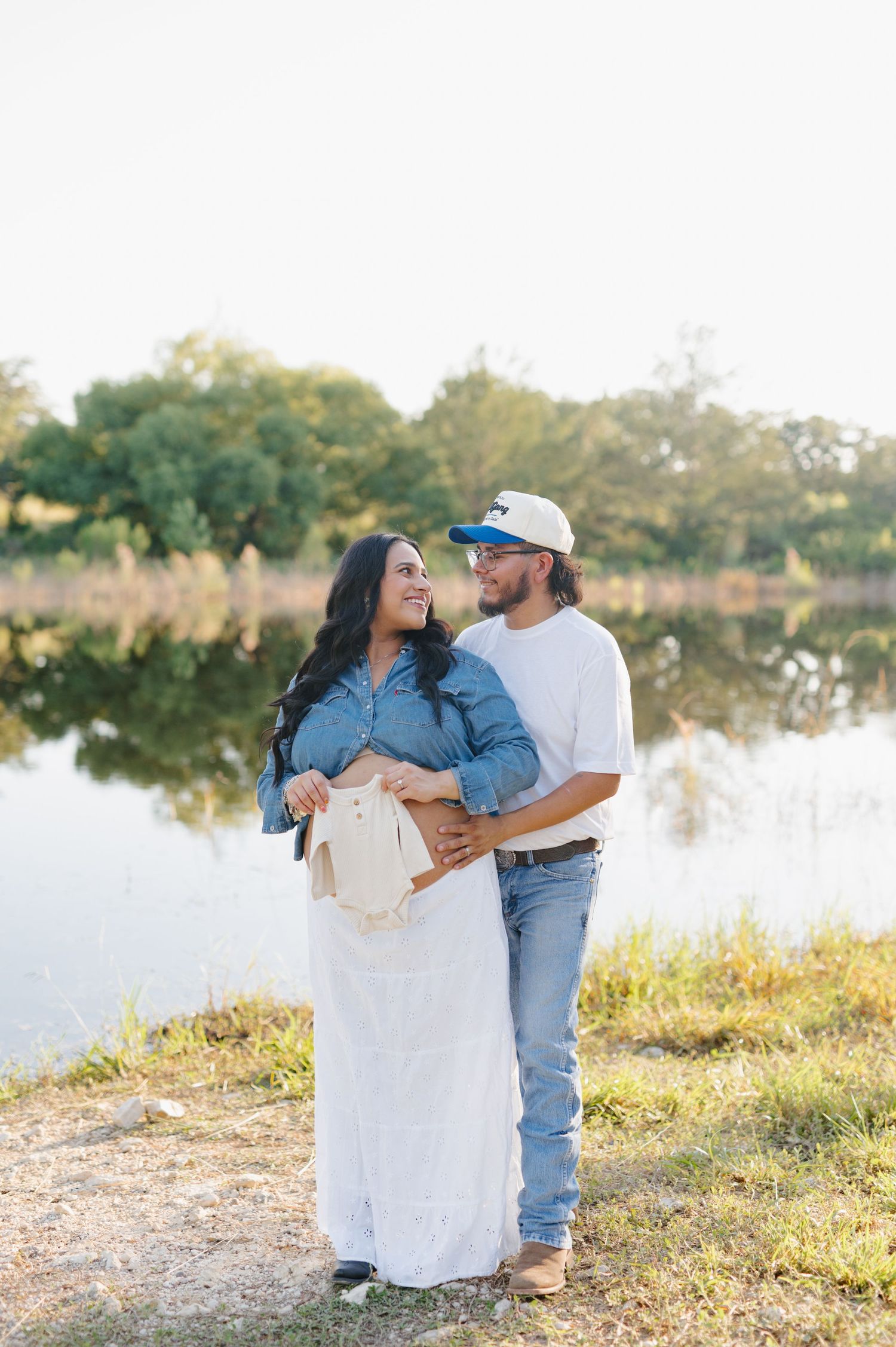 A couple embraces by a serene lake during golden hour photography session.