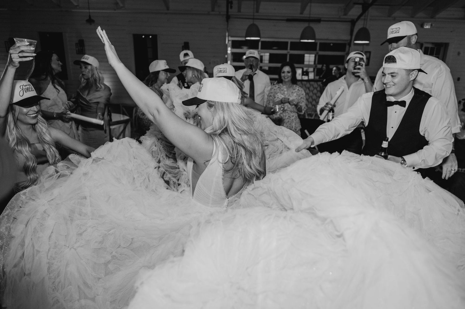 A black and white image of a bride in a large, fluffy wedding dress dancing with a man in a tuxedo.