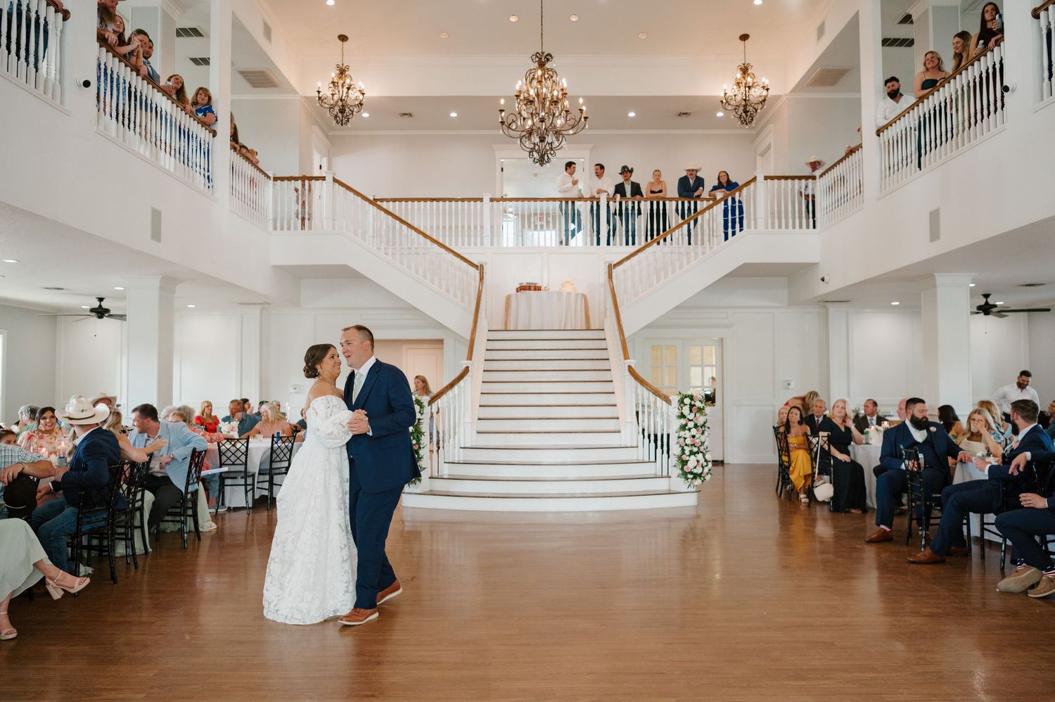 A panoramic view of an elegant wedding reception venue with white stairs and floral decorations.