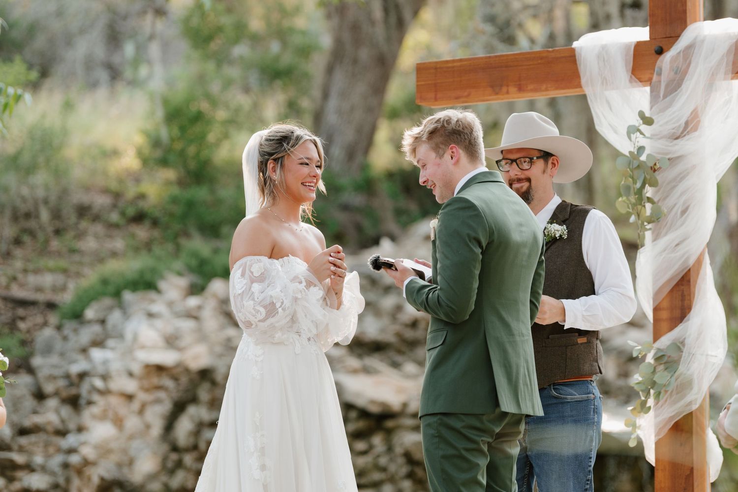 A couple shares a romantic moment during their outdoor wedding ceremony surrounded by natural scenery.