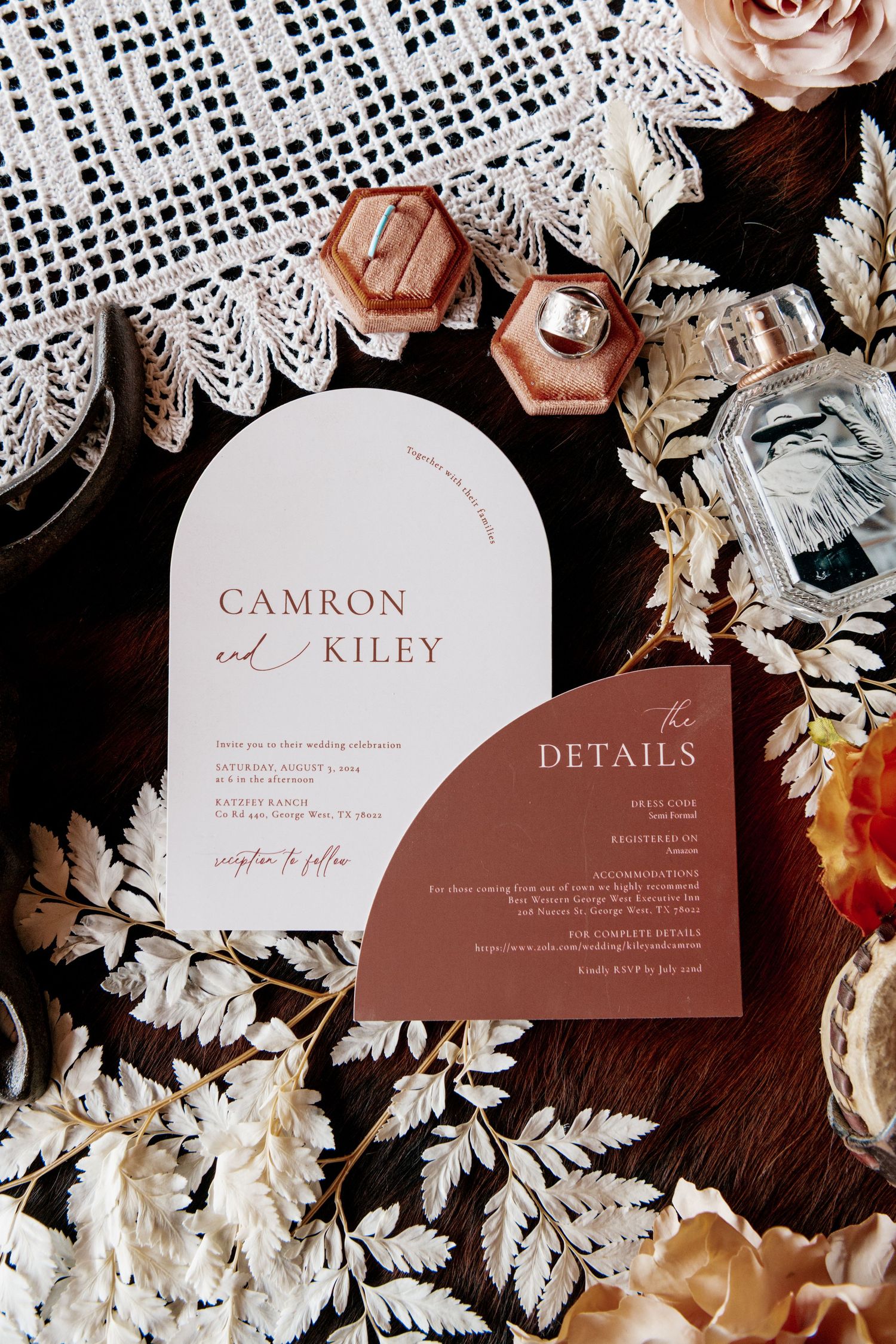 Modern wedding invitation suite with arch-shaped cards in white and terracotta tones alongside lace and floral details.