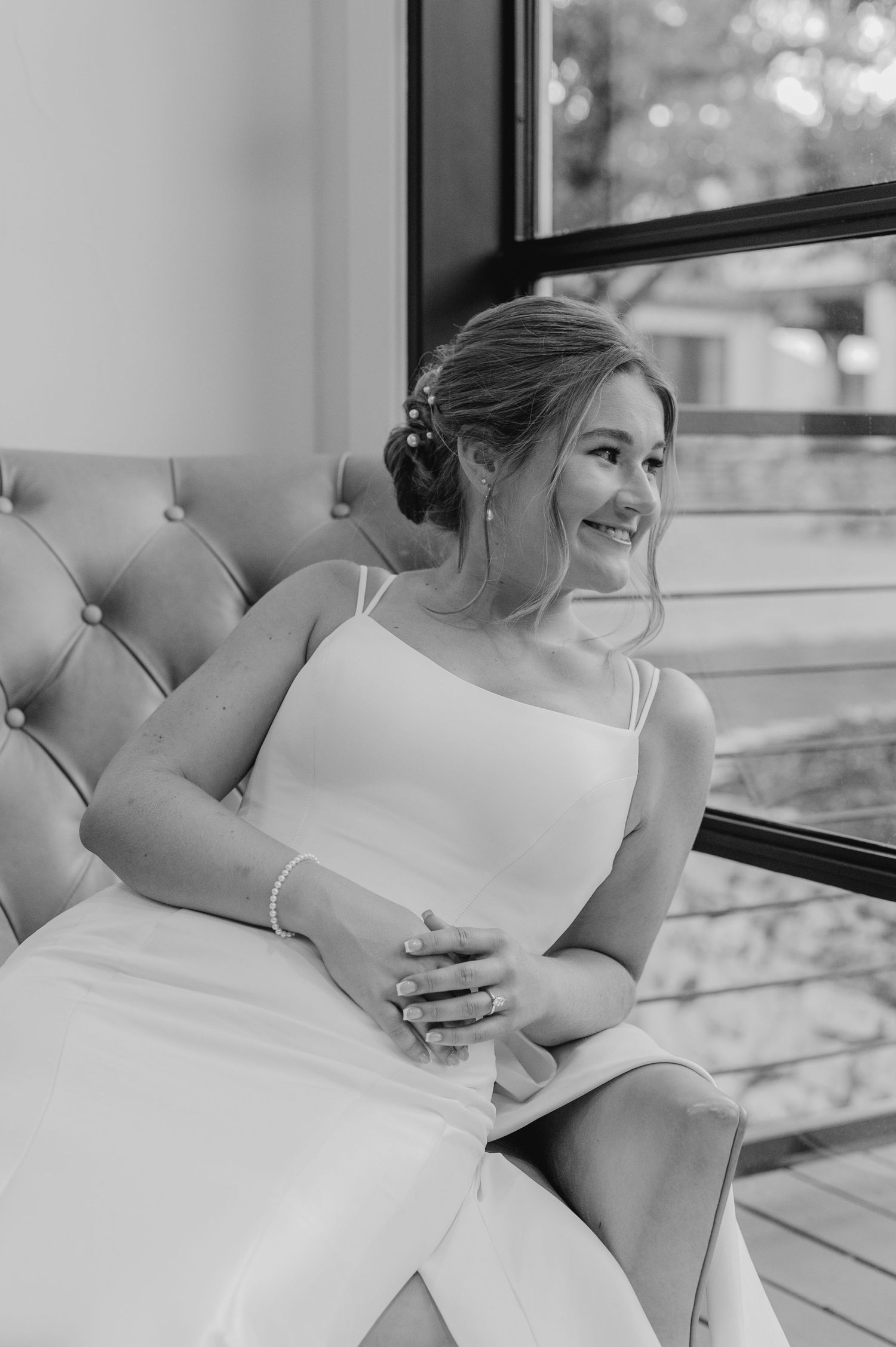 Black and white indoor bridal portraits showing genuine laughter against tufted furniture.