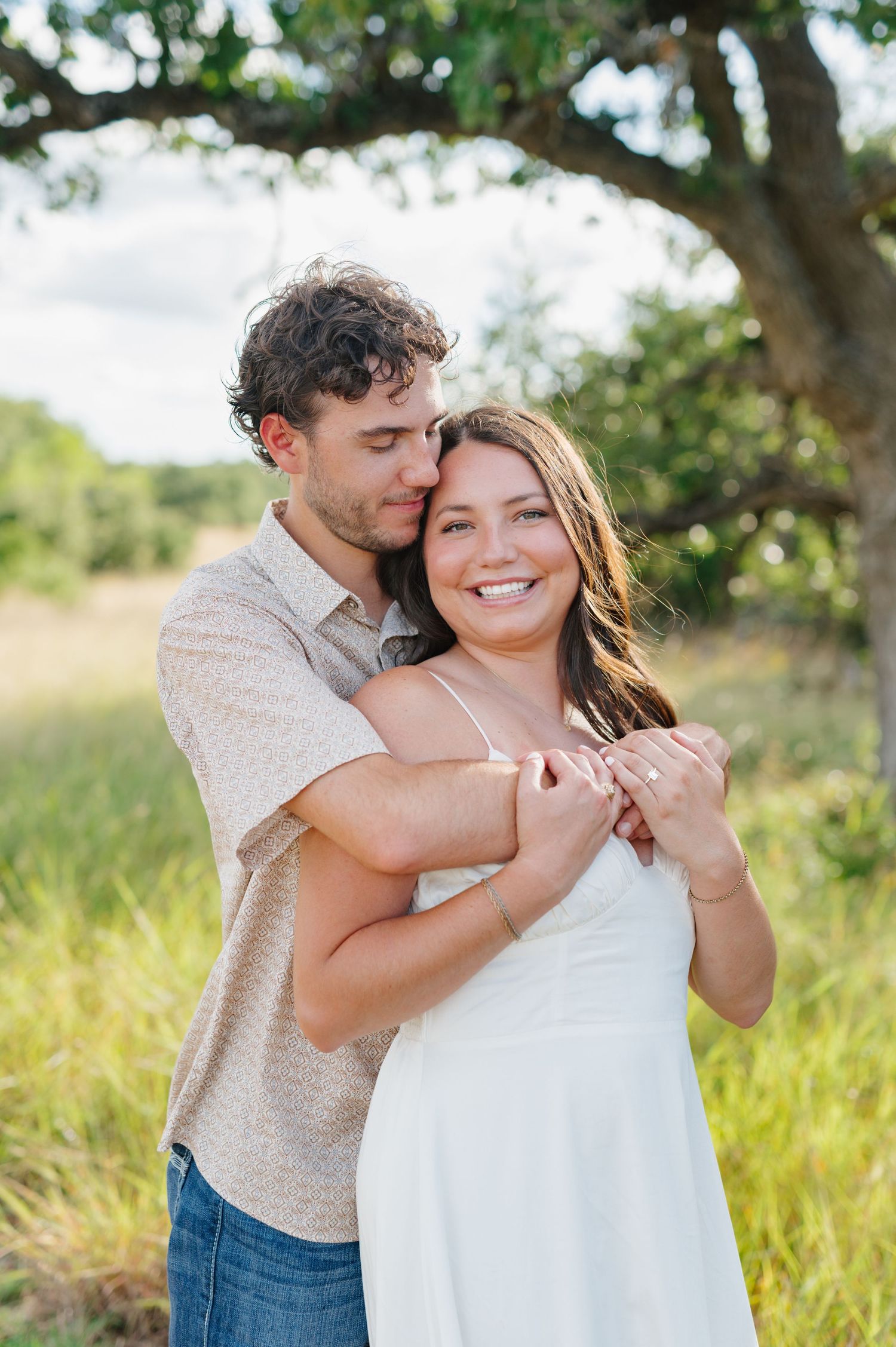 Romantic outdoor photoshoot with couple embracing in golden sunlight and natural scenery.