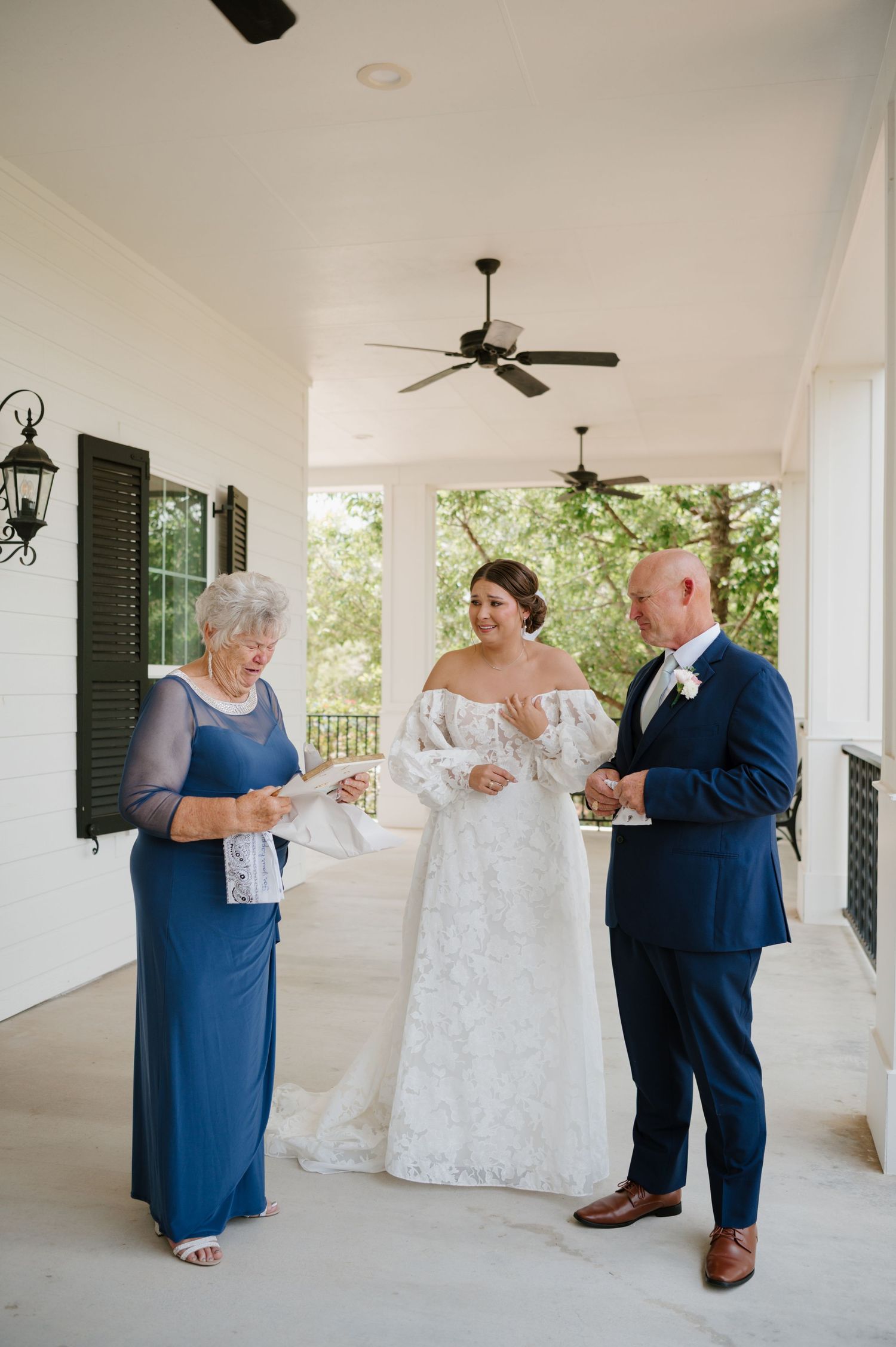 Wedding party gathered on a white columned porch for preparation photos.