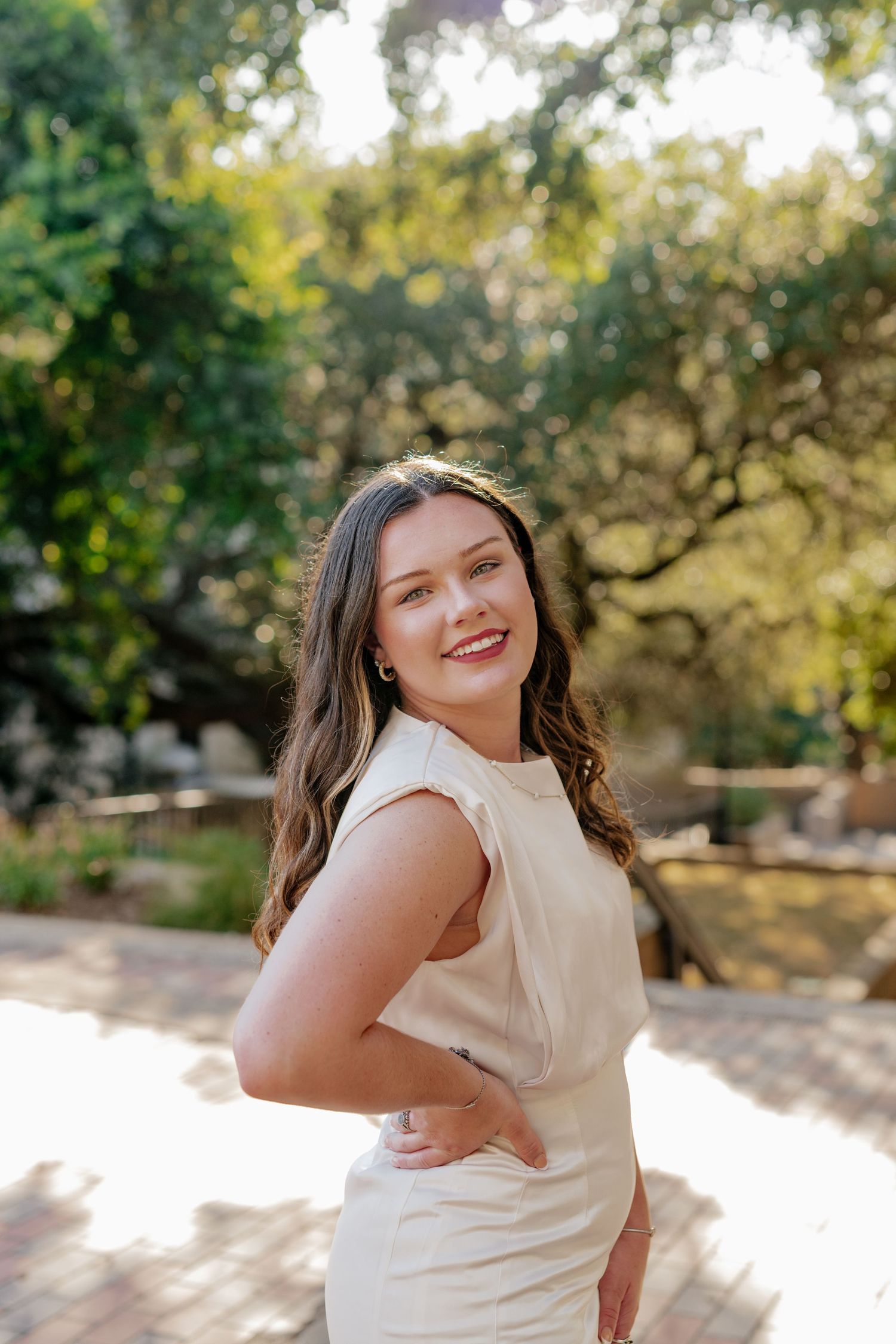 Senior session at Texas State University. The senior poses underneath a tree canopy on campus during golden hour.