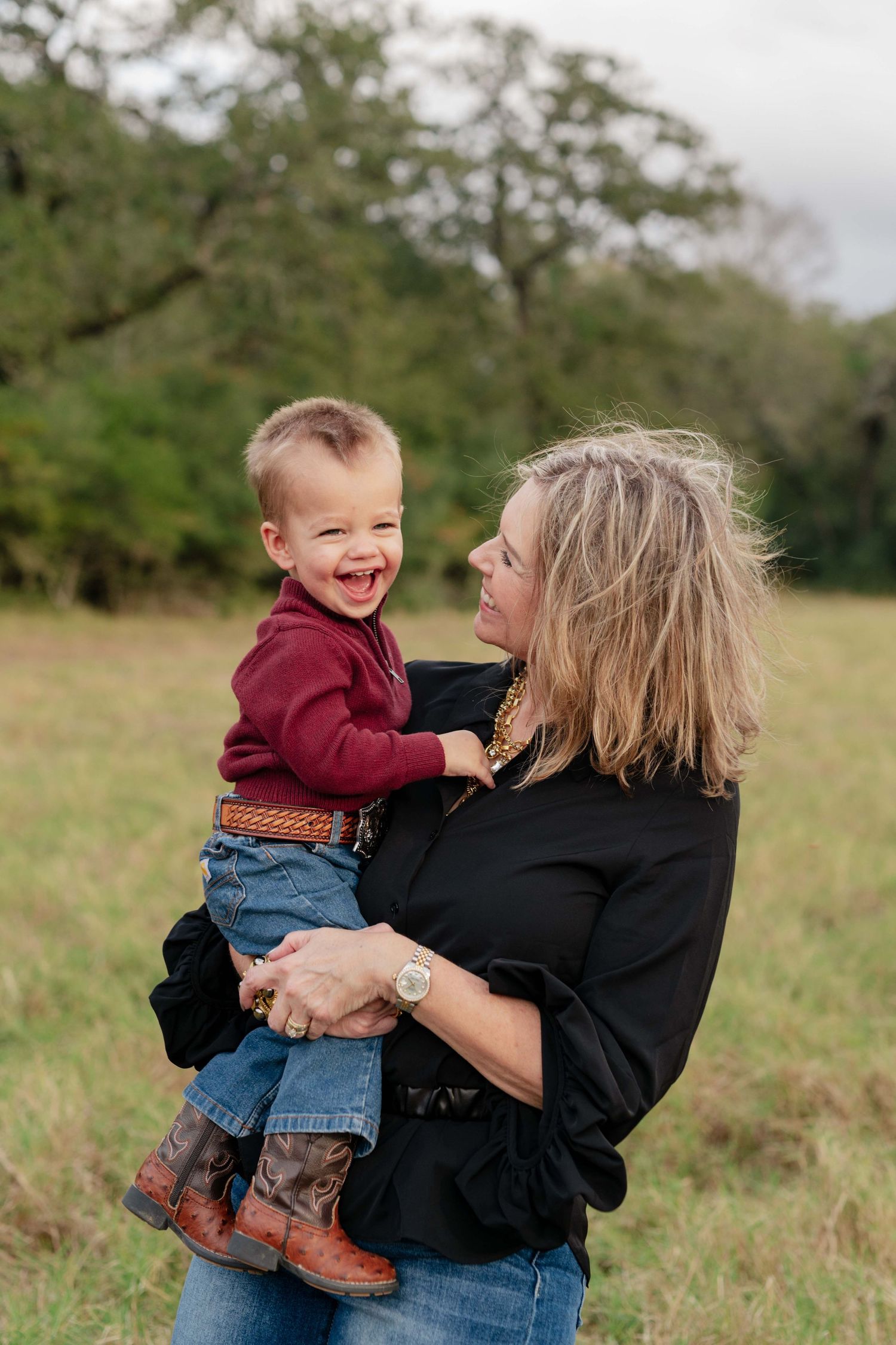 Mother and toddler share a joyful moment outdoors in a grassy field.