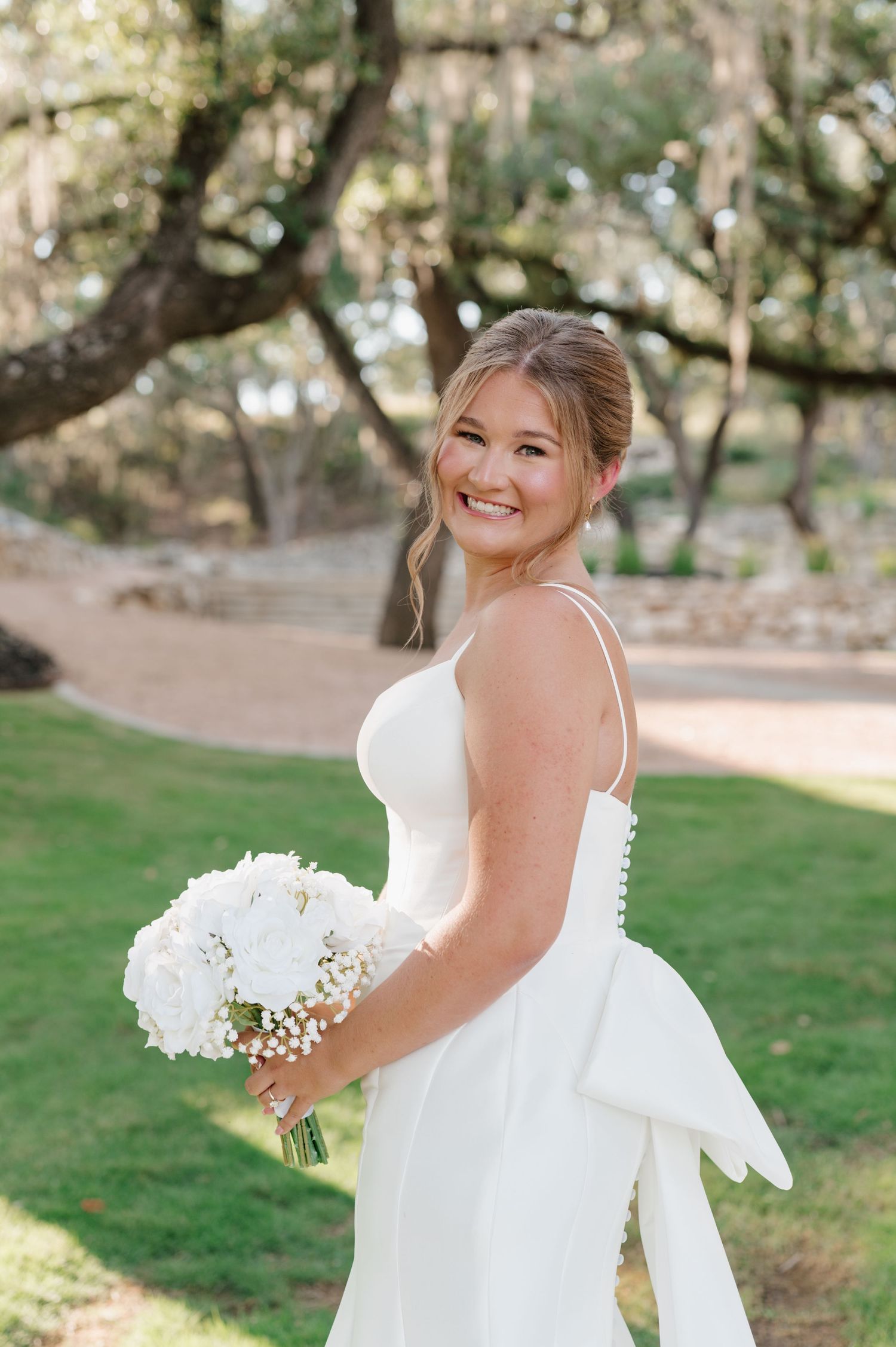 Candid bridal portraits showcase a beautiful white wedding dress and bouquet in an outdoor setting.