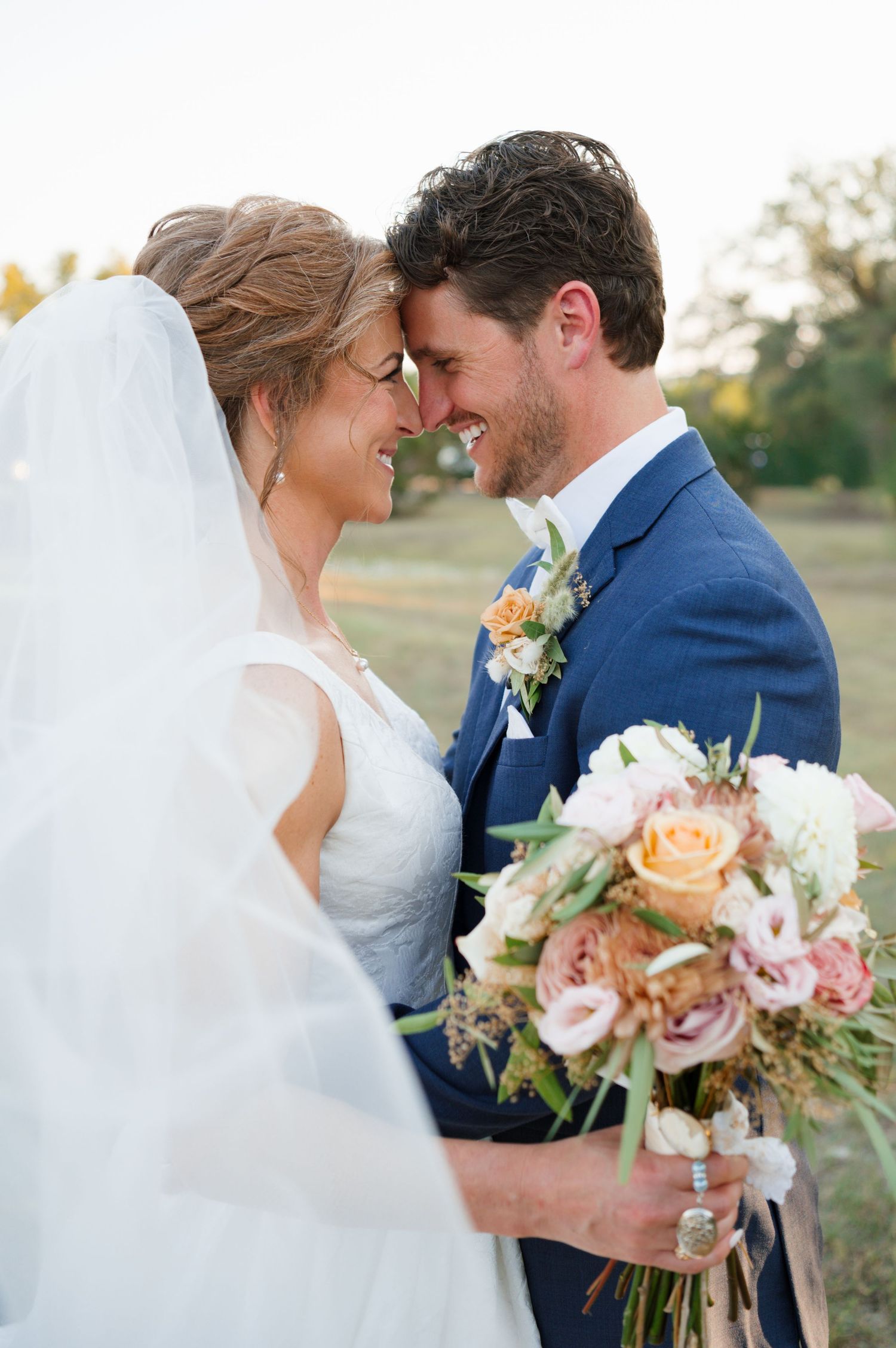 A romantic wedding couple shares intimate kisses in a series of outdoor sunset portraits with peach and pink bouquet details.