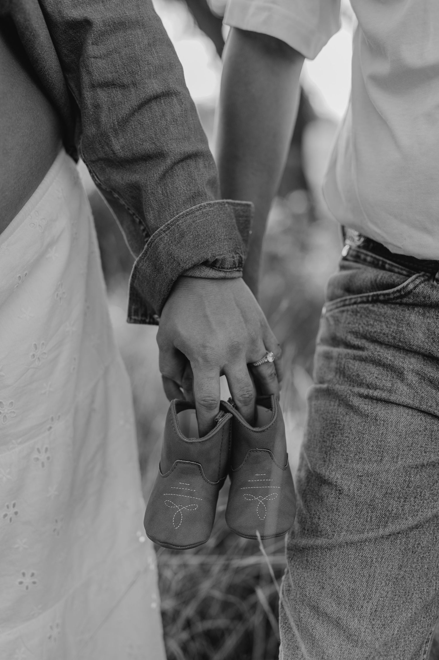 Close-up view of someone wearing denim jeans and boots in a black and white wedding photo.