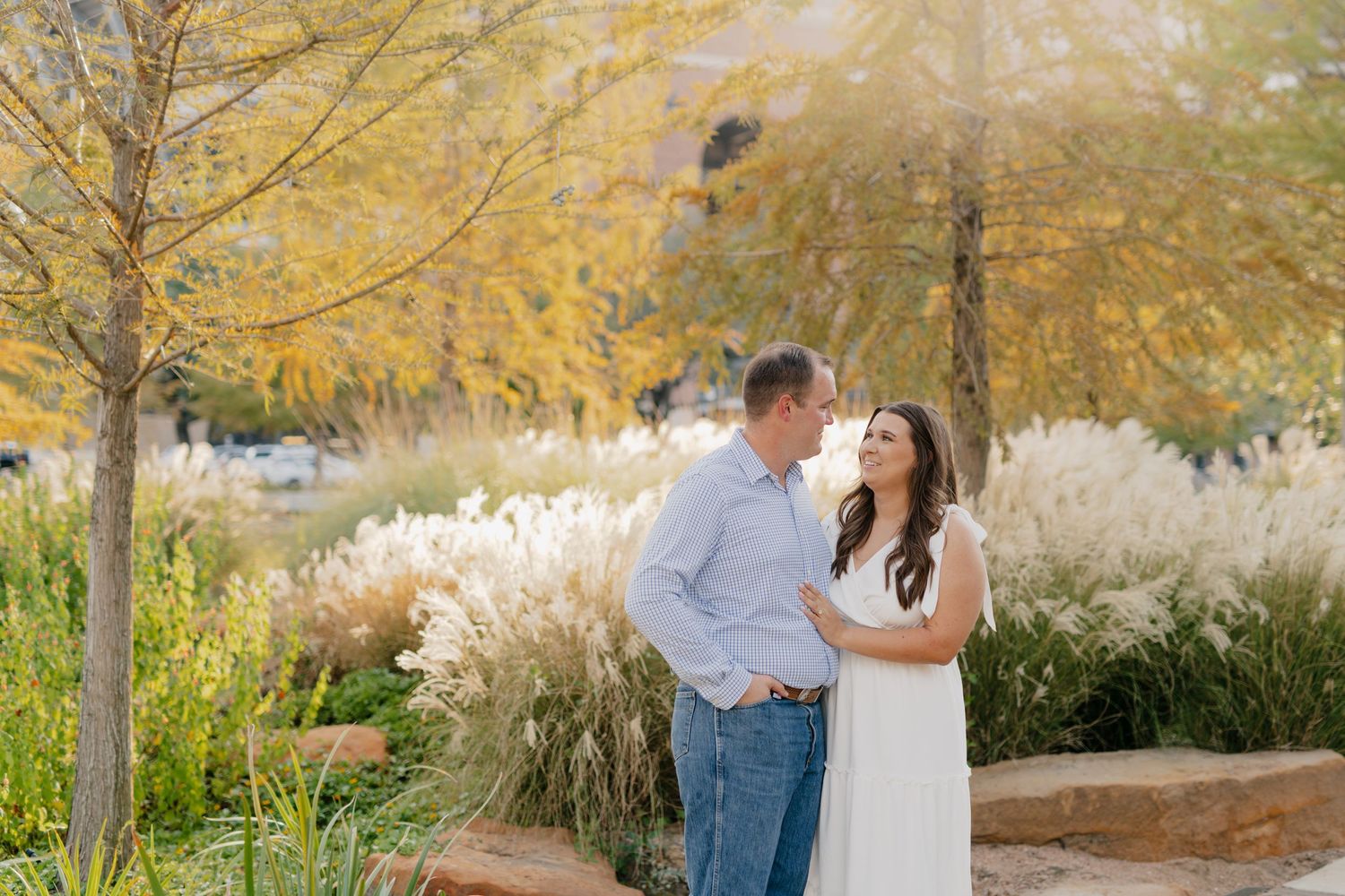 Romantic couple shares a tender moment on wooden walkway surrounded by fall foliage.