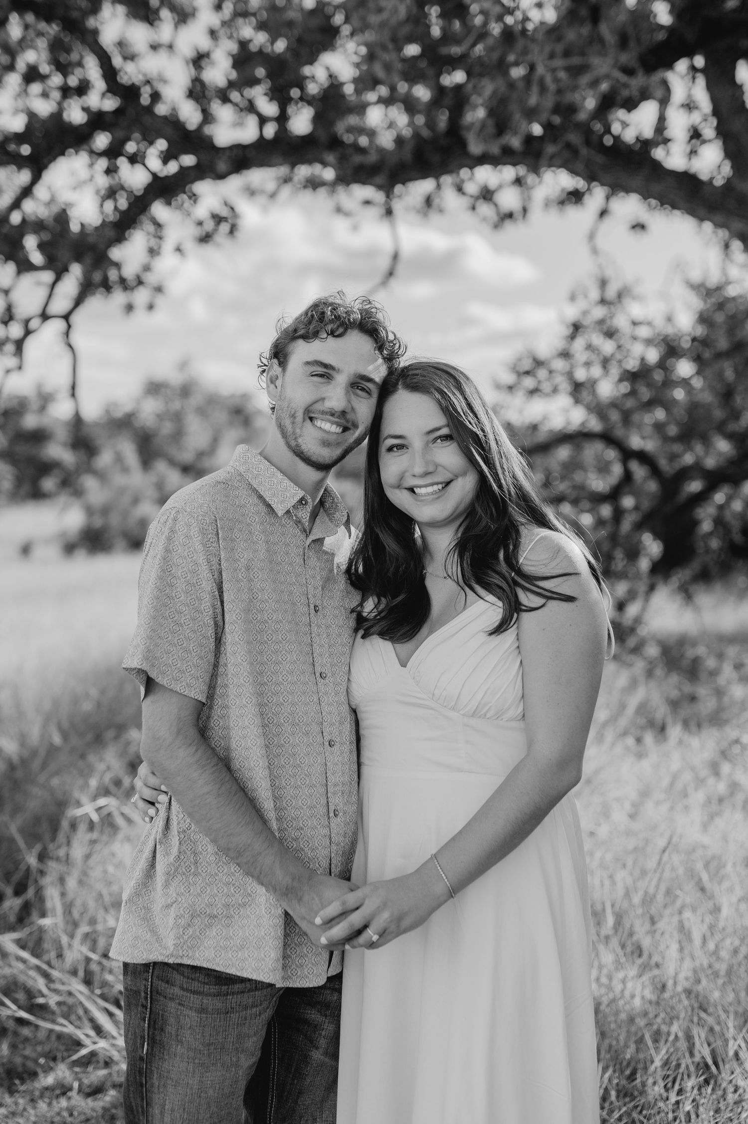 A romantic black and white photo series of a couple embracing in a sunny outdoor setting.