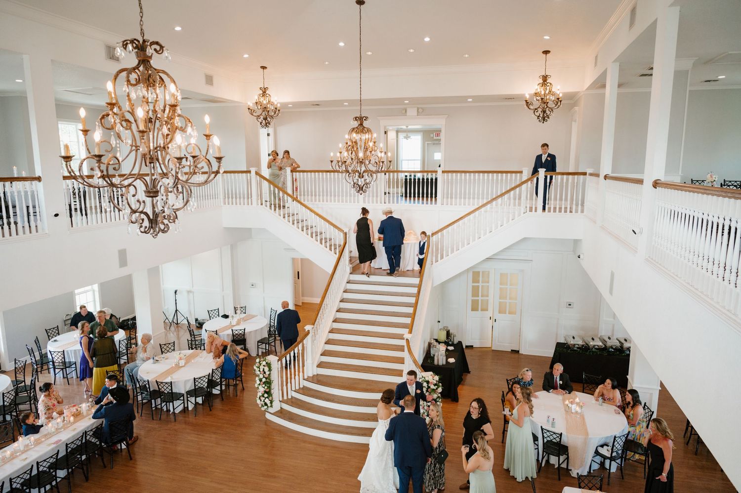 Grand ballroom decorated with crystal chandeliers and white decor for an elegant wedding reception.