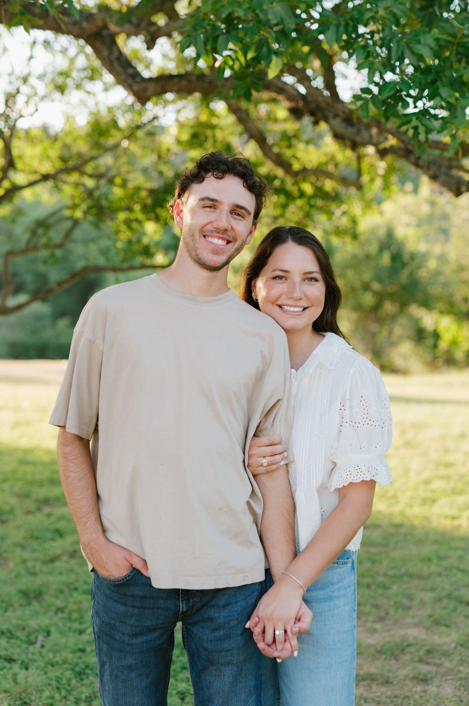 A couple shares tender moments during a casual outdoor photo session in a sunlit natural setting.