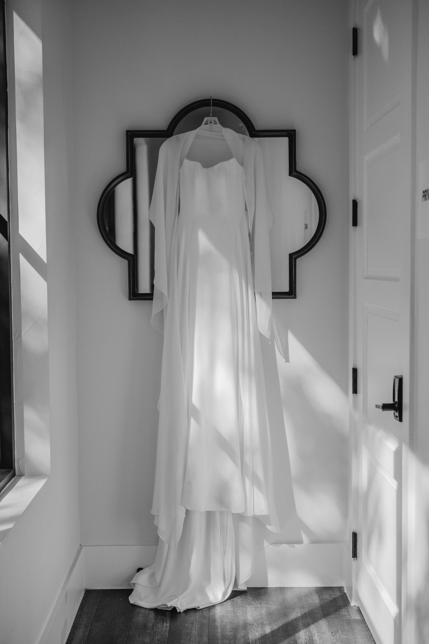 White wedding dresses hanging in sequence along a hallway creating an ethereal display.