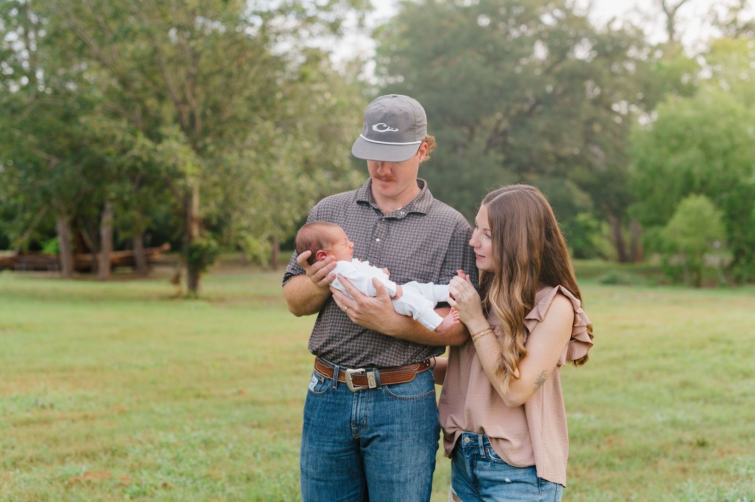 Family enjoying tender moments together in a sunlit outdoor park setting while taking photographs.