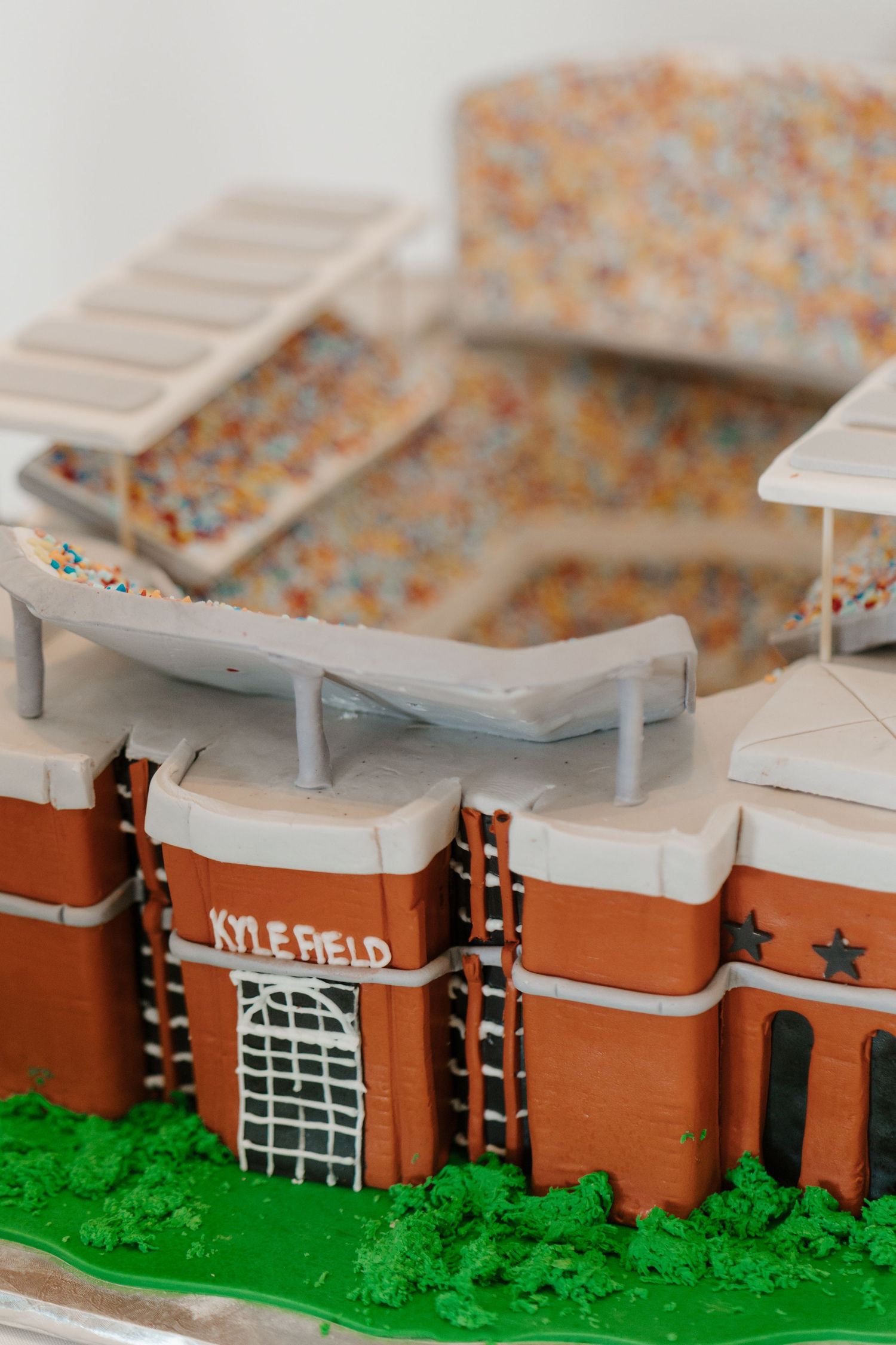 Close-up view of a miniature architectural model showing orange brick building segments with white trim labeled Lyle Field.